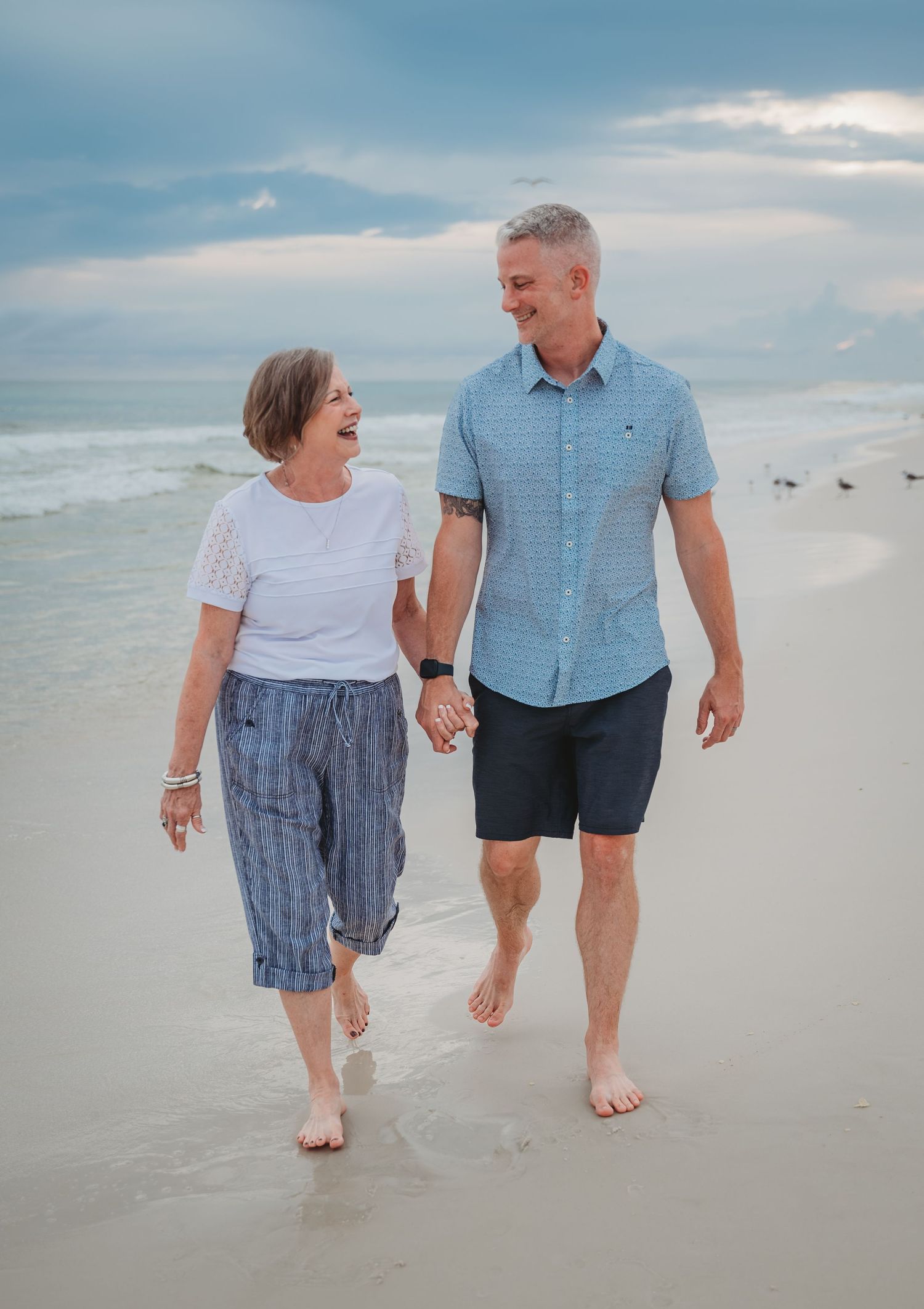 Couple takes a romantic stroll together along the shoreline of a peaceful beach at dusk in Panama City Beach.
