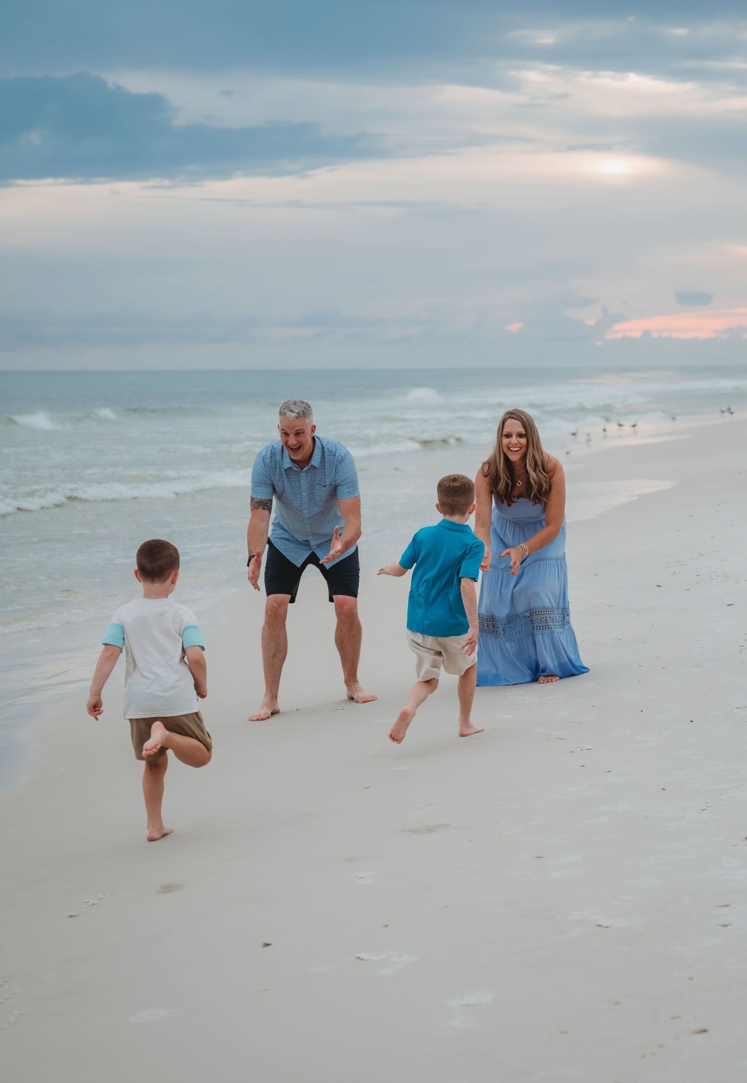 Family members walking along a white sandy beach at sunset while waves roll in from the ocean in Panama City Beach.