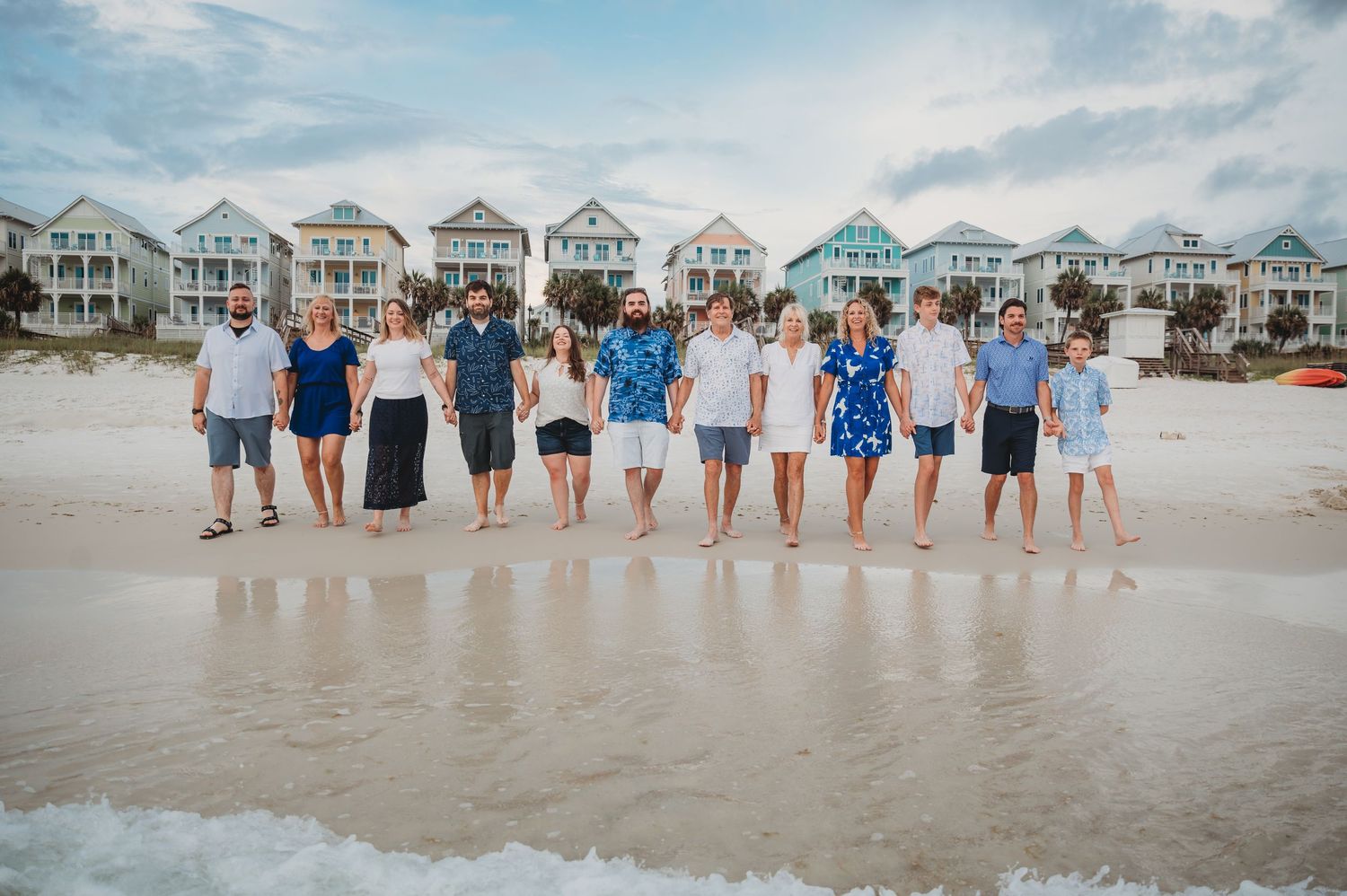 Group of people in coordinated blue and white outfits stand on a sunny beach with beach houses in background in Panama City Beach.