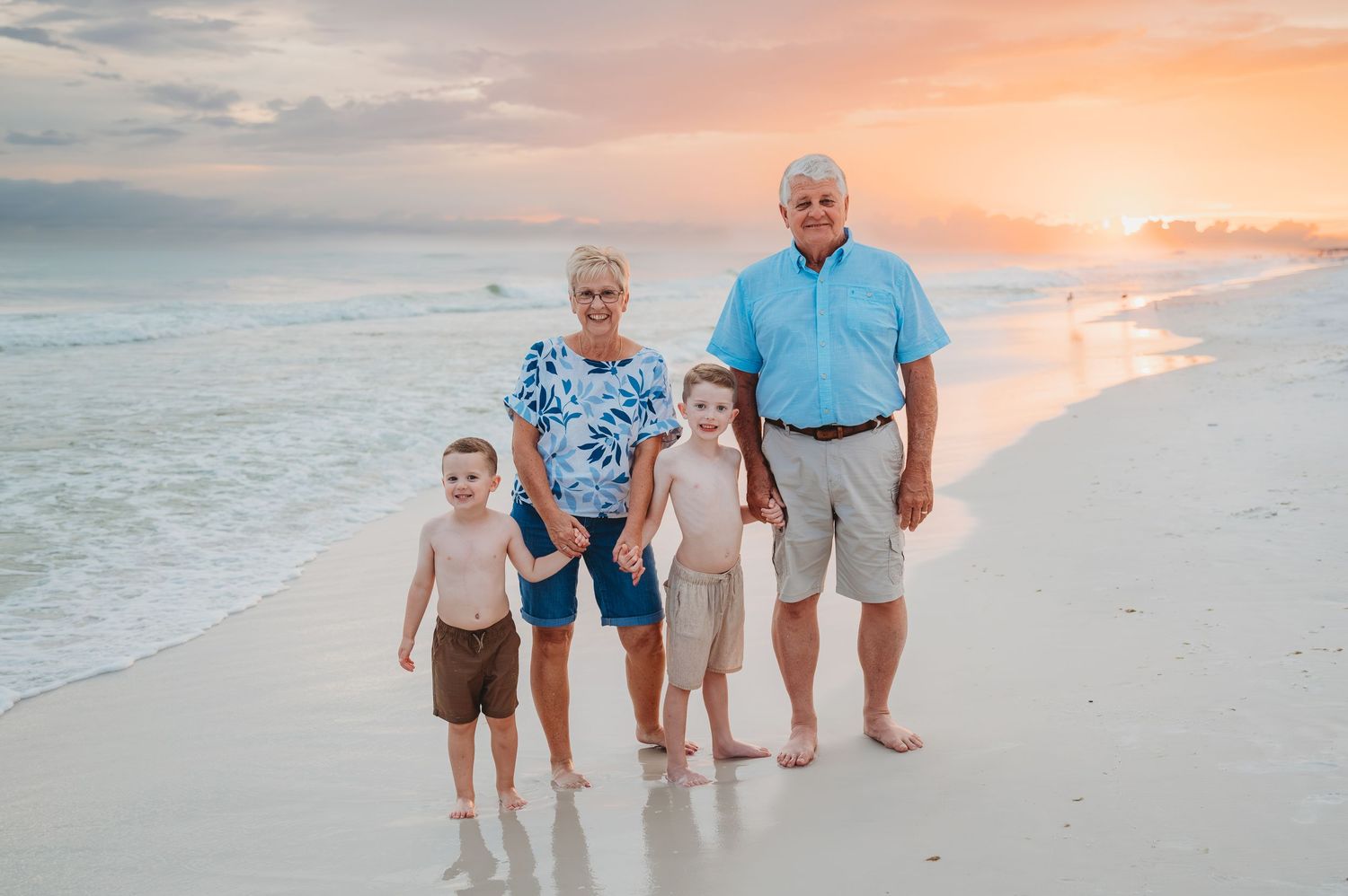 People walking together along a scenic beach shoreline during a beautiful orange sunset at the ocean in Panama City Beach.