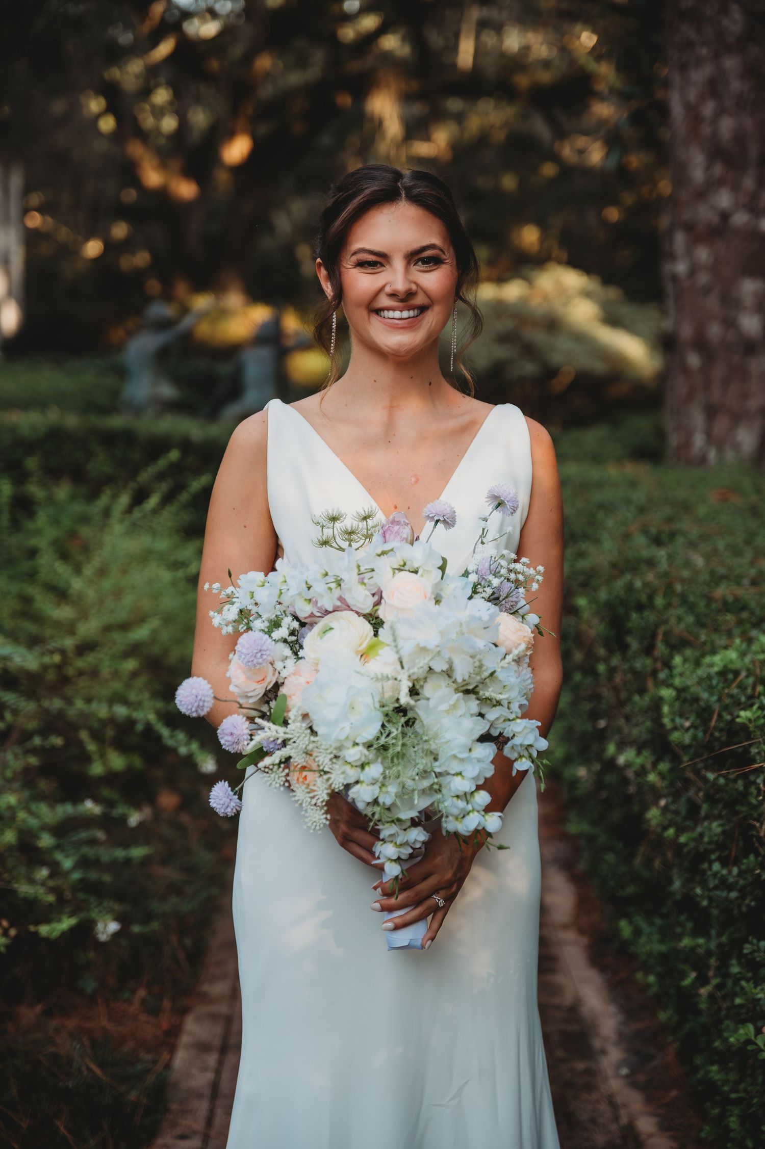 Bride in white sleeveless wedding dress holds beautiful bouquet of white and blush flowers during a Panama City Beach wedding.