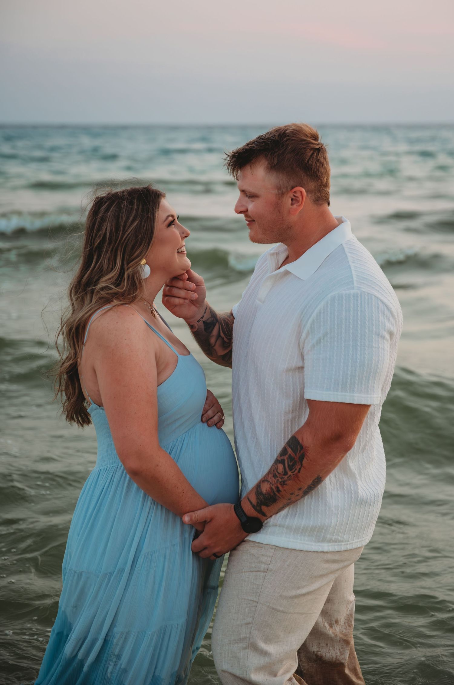 A romantic couple embraces on a 30A beach at sunset with ocean waves in the background.