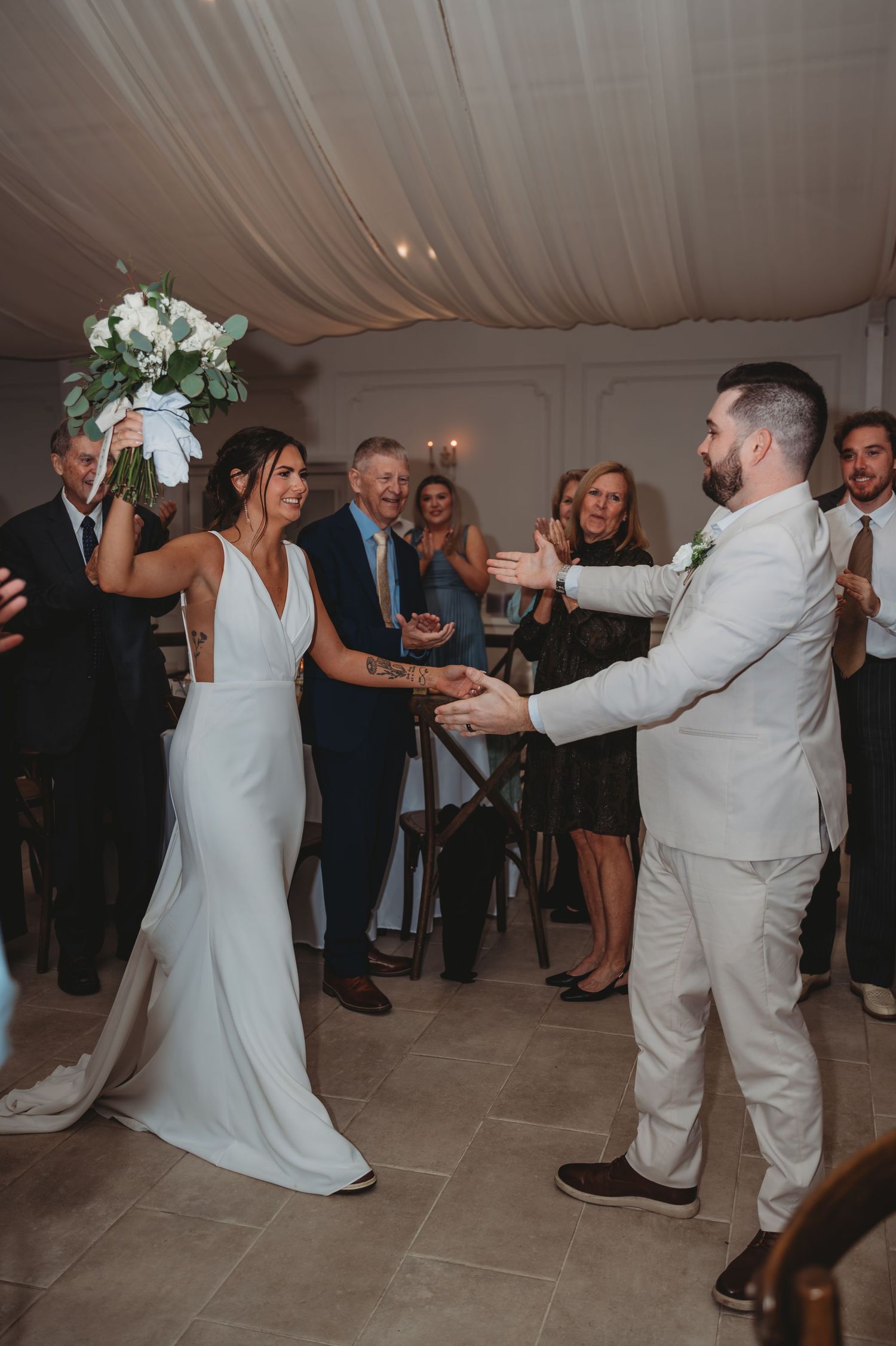 Wedding couple dances together under a white tent as guests watch during a Panama City Beach wedding reception.