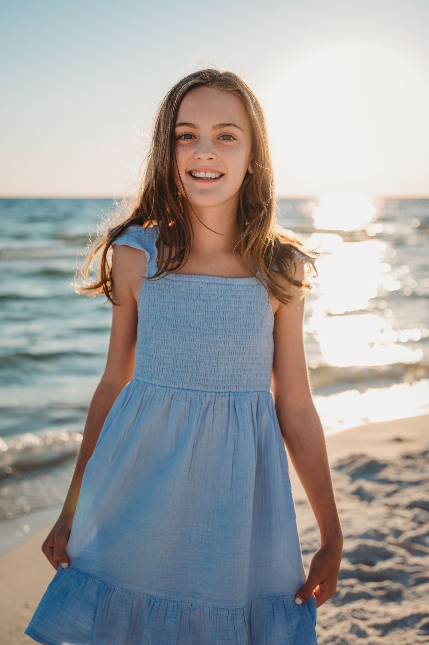 A light blue cotton sundress flows in the 30A ocean breeze as someone poses on a sunny beach at golden hour.