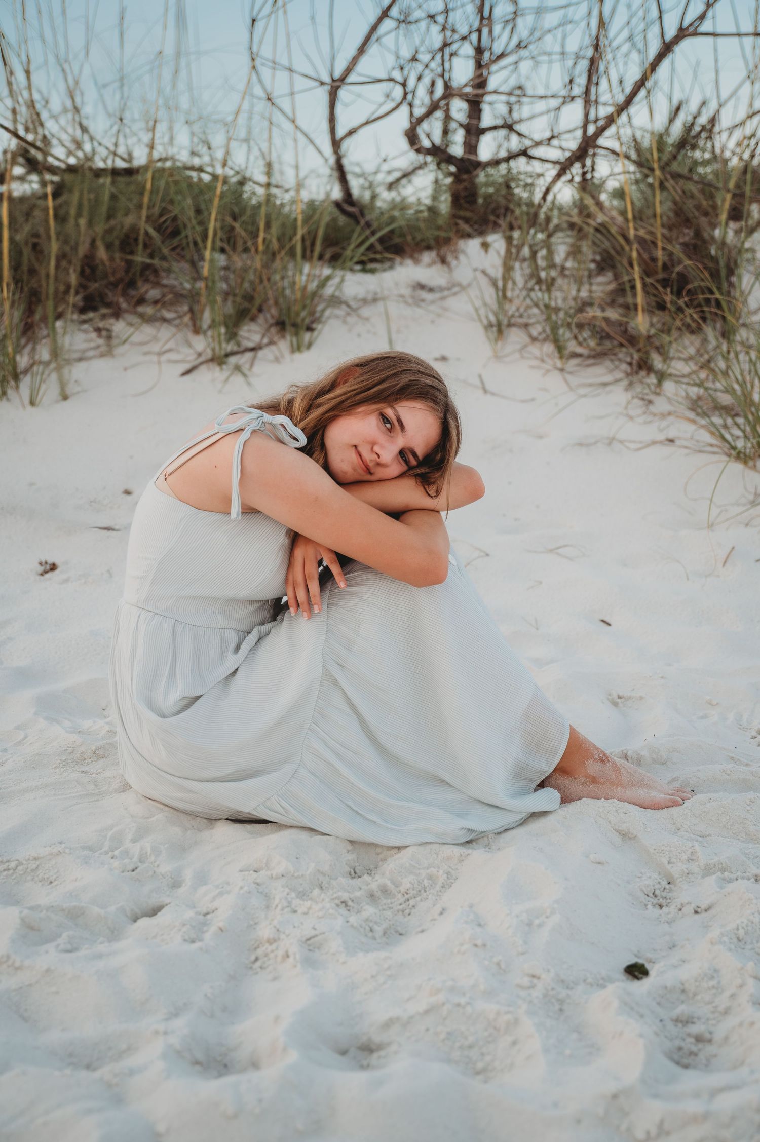 A dreamy portrait series of someone in a white dress reclining on pristine white sand at dusk in Panama City Beach.