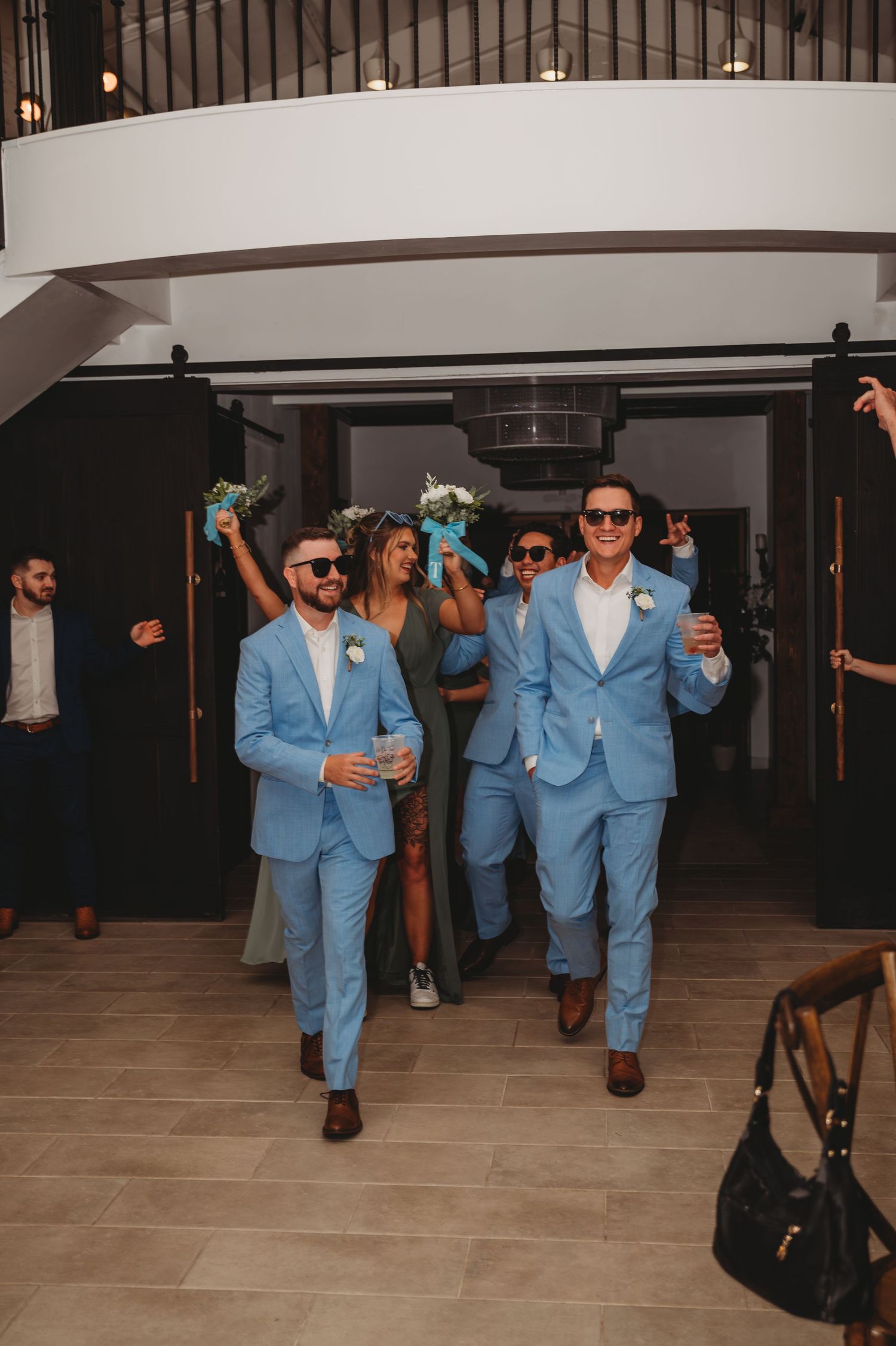 Groomsmen wearing matching light blue suits walk in to the reception during a Panama City Beach wedding.
