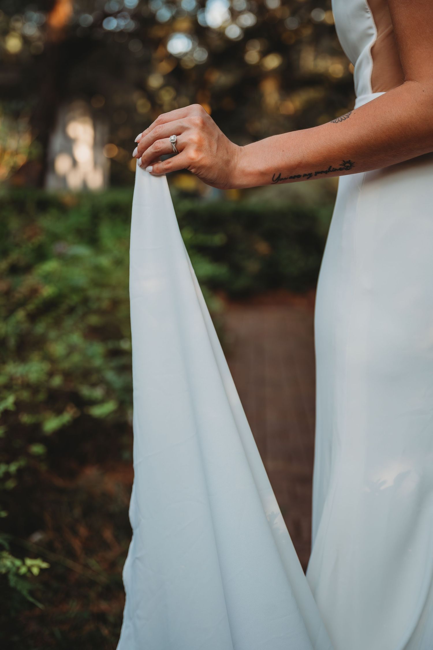 Bride holding the flowing fabric of a white wedding dress against a natural outdoor background during a Panama City Beach wedding.