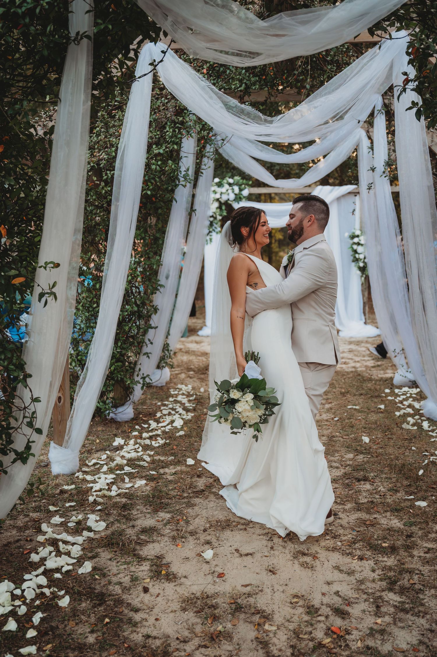 A romantic wedding couple shares intimate moments under flowing white fabric drapes in Panama City Beach.