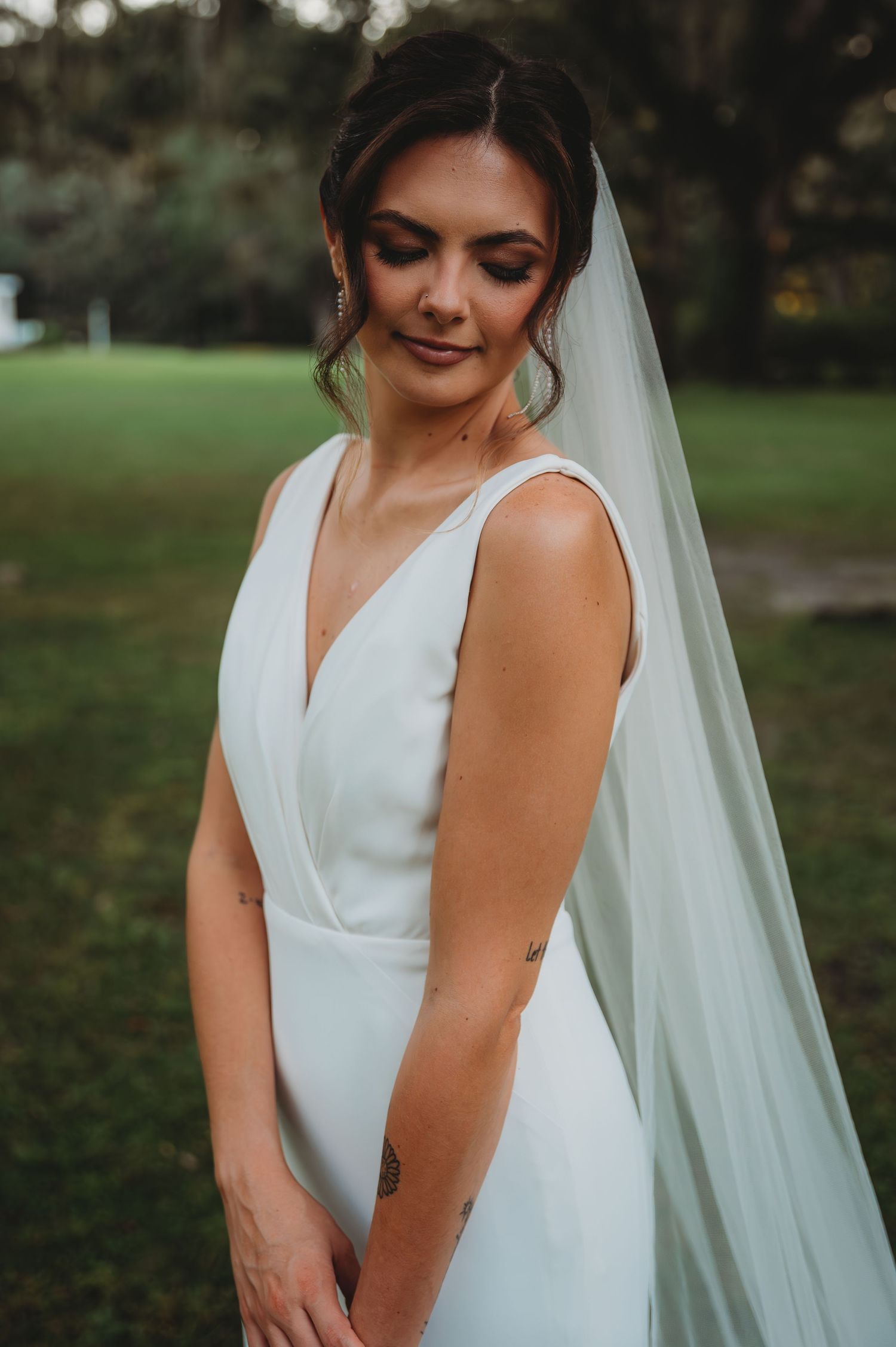 A bride in an elegant white sleeveless wedding dress with a flowing veil stands during a Panama City Beach wedding.
