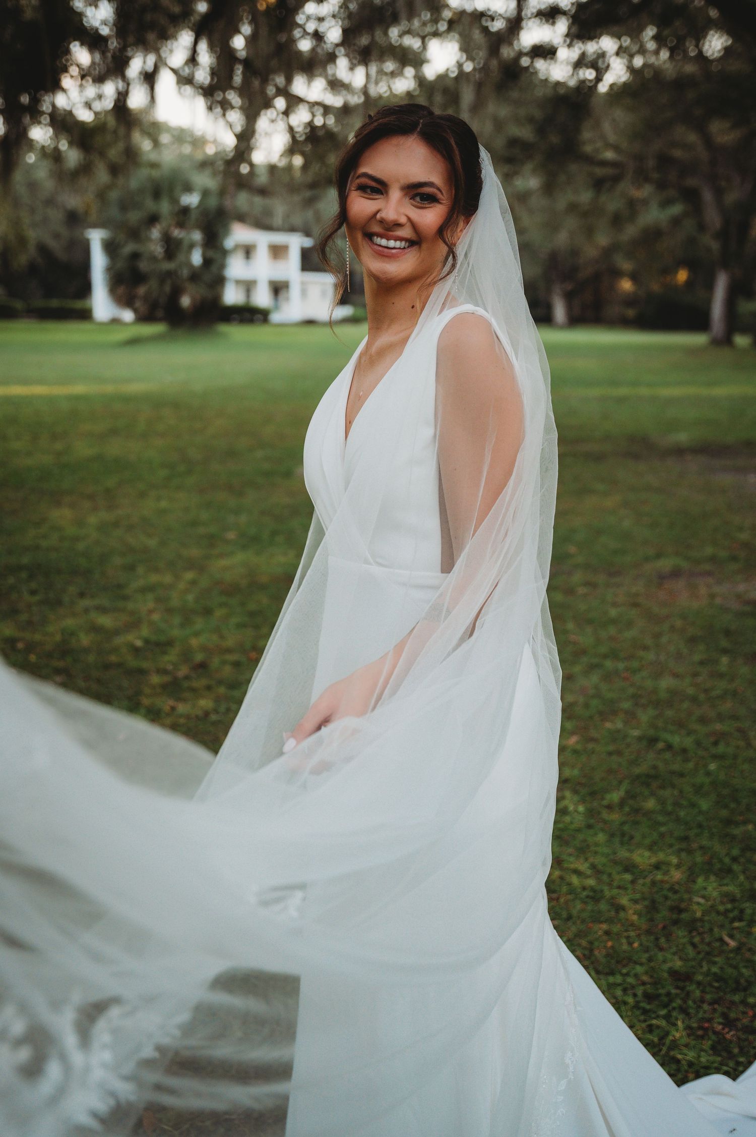 A bride in a white wedding dress twirls outdoors, making her veil and gown float gracefully in the air during a Panama City Beach wedding.