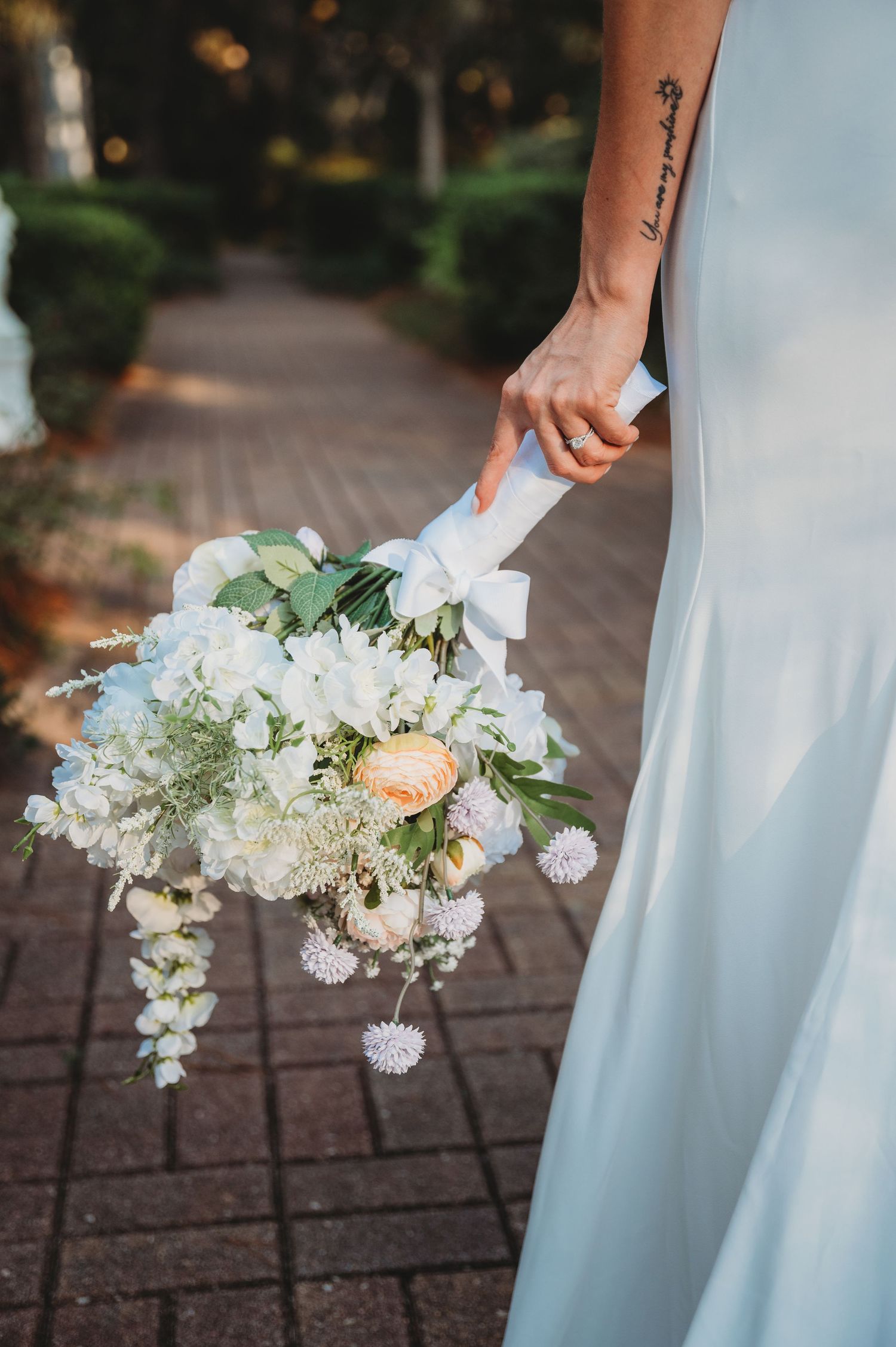 Elegant white and peach floral bouquet held against a wedding dress during a Panama City Beach wedding.