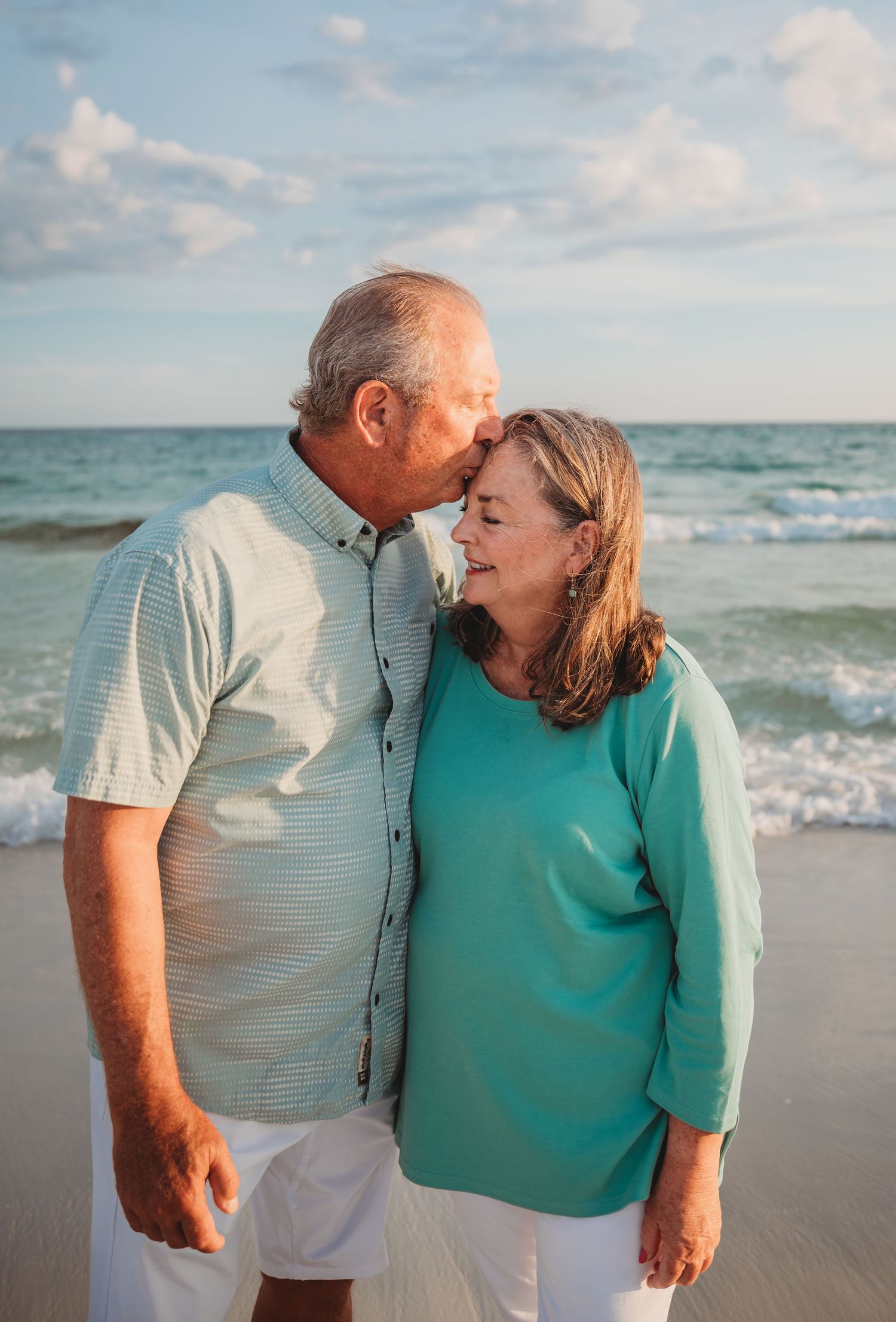 A loving elderly couple shares tender moments together while walking along a beautiful beach at sunset in Panama City Beach.