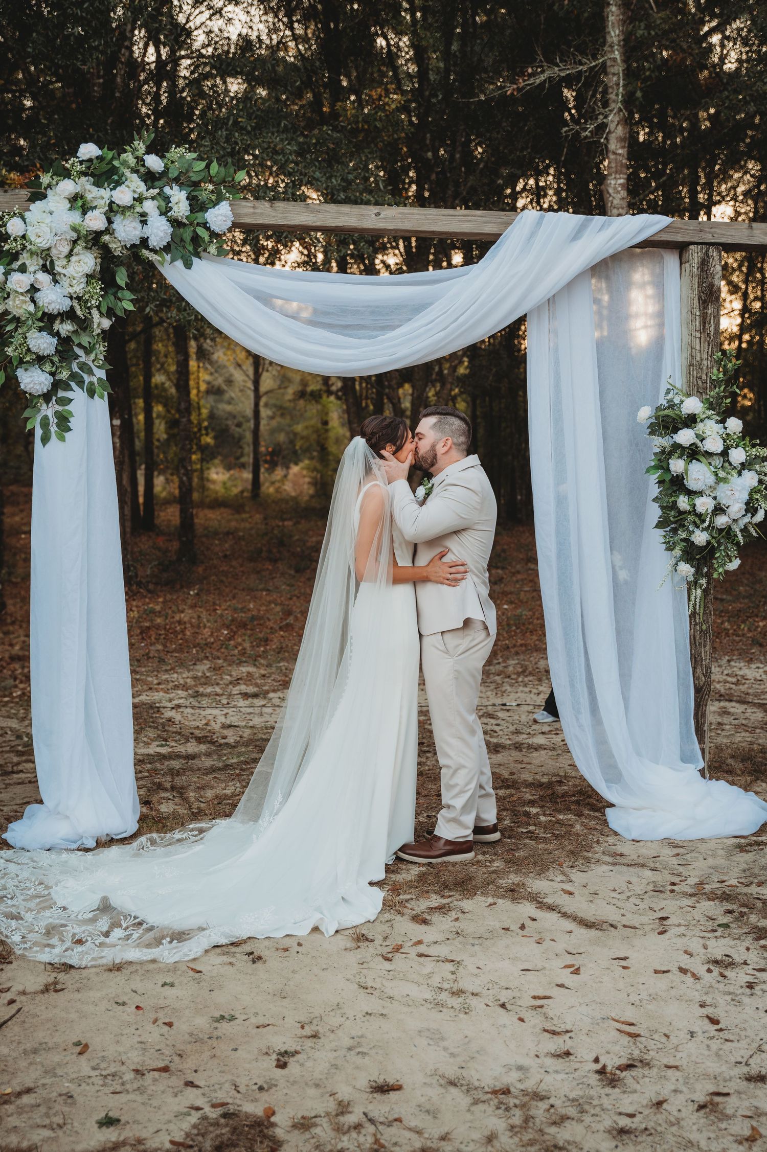 A romantic outdoor wedding ceremony setup with flowing white fabric drapes and floral arrangements in Panama City Beach.