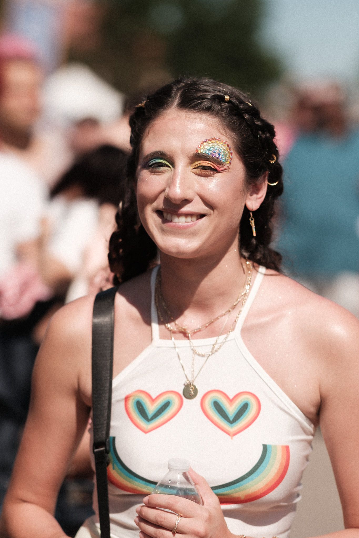 A person wearing a cheerleader outfit with a white top featuring green and orange heart designs poses and smiles outdoors.