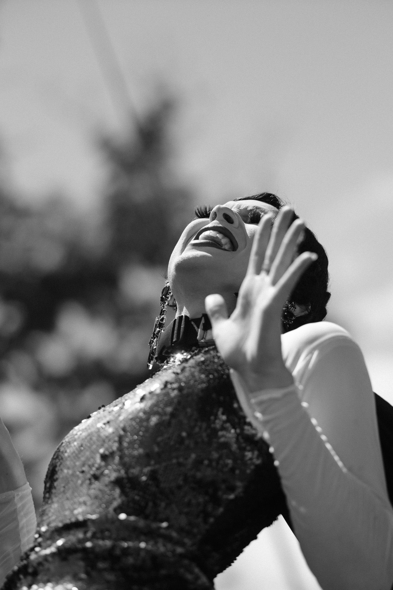 Black and white sequence showing someone throwing their head back in joyful laughter outdoors.
