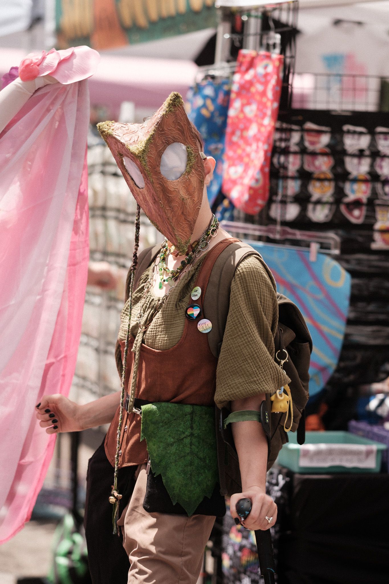 Person in steampunk style costume with horse mask and goggles at outdoor event.