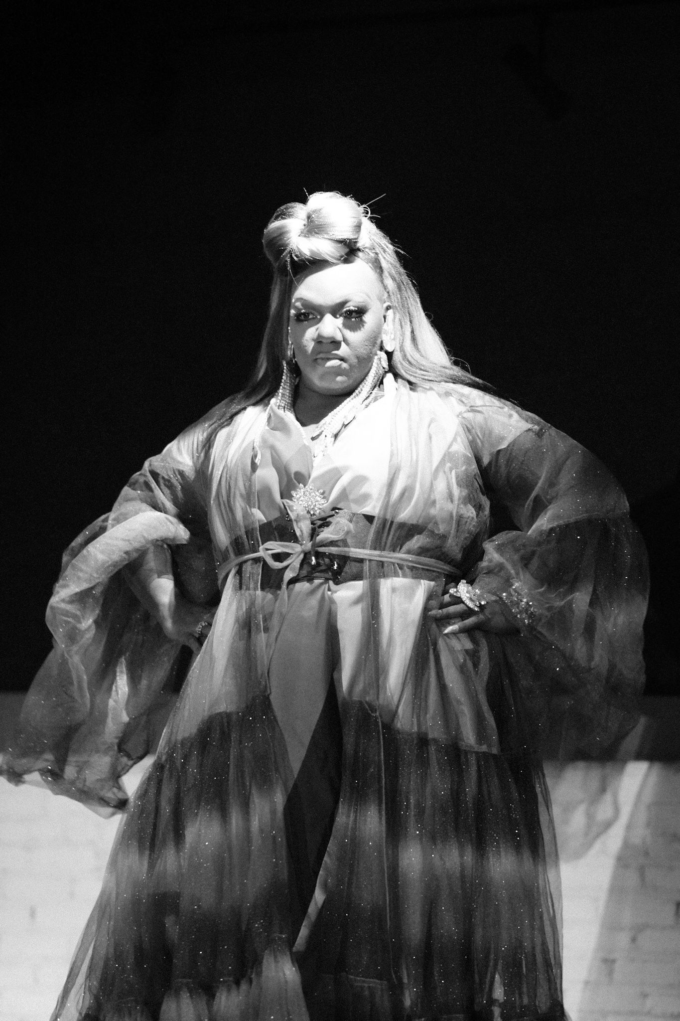 Dramatic black and white portrait of performer in flowing traditional Asian-inspired robe.