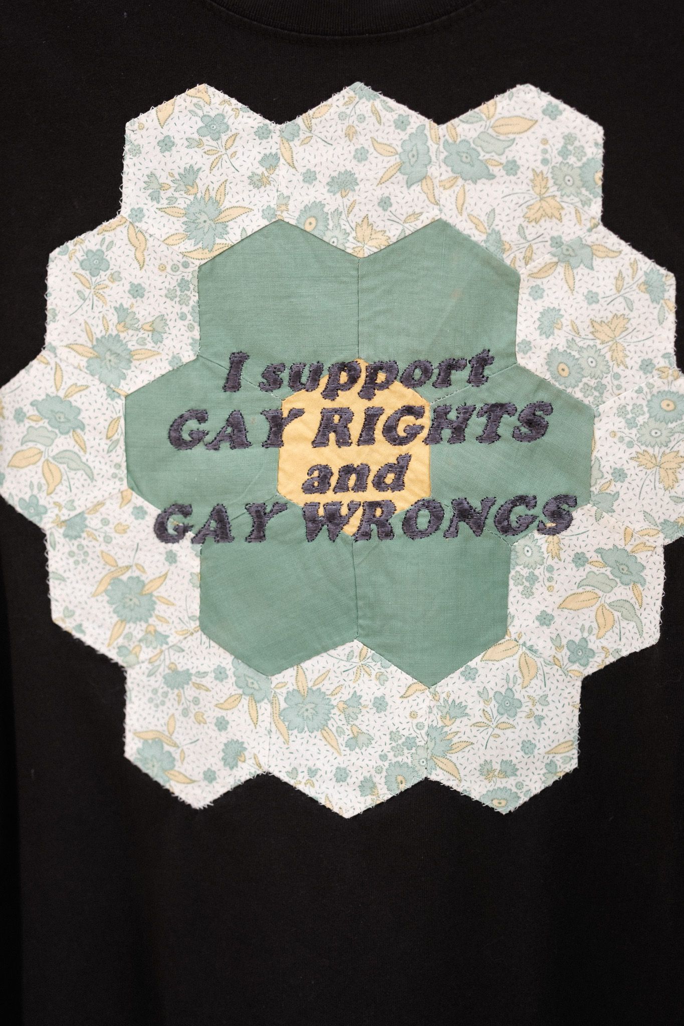 Art piece showing text 'gay rights' in angular hexagonal segments with floral patterned background and dark edges.