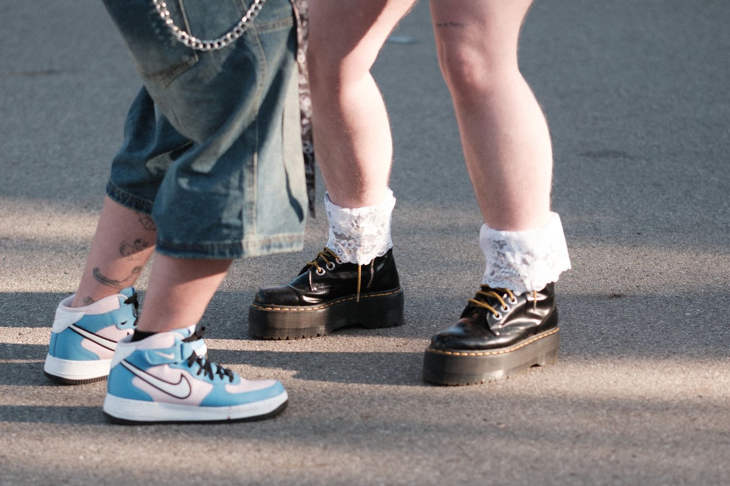 Close-up view of feet showing contrasting sneakers and socks between two people standing together.