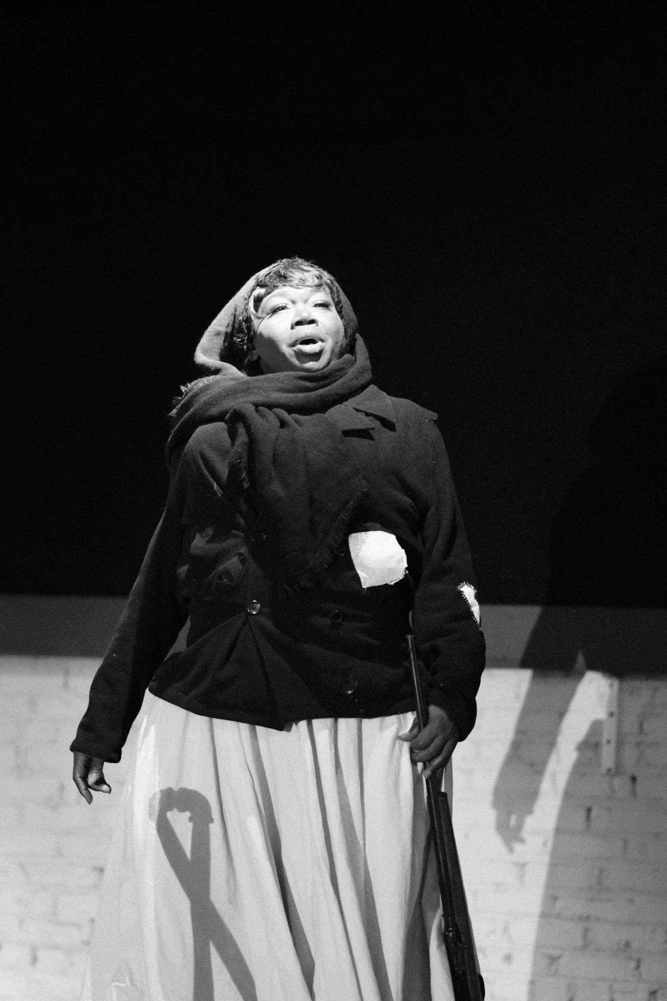 Dramatic black and white photo of performer in period costume on stage.