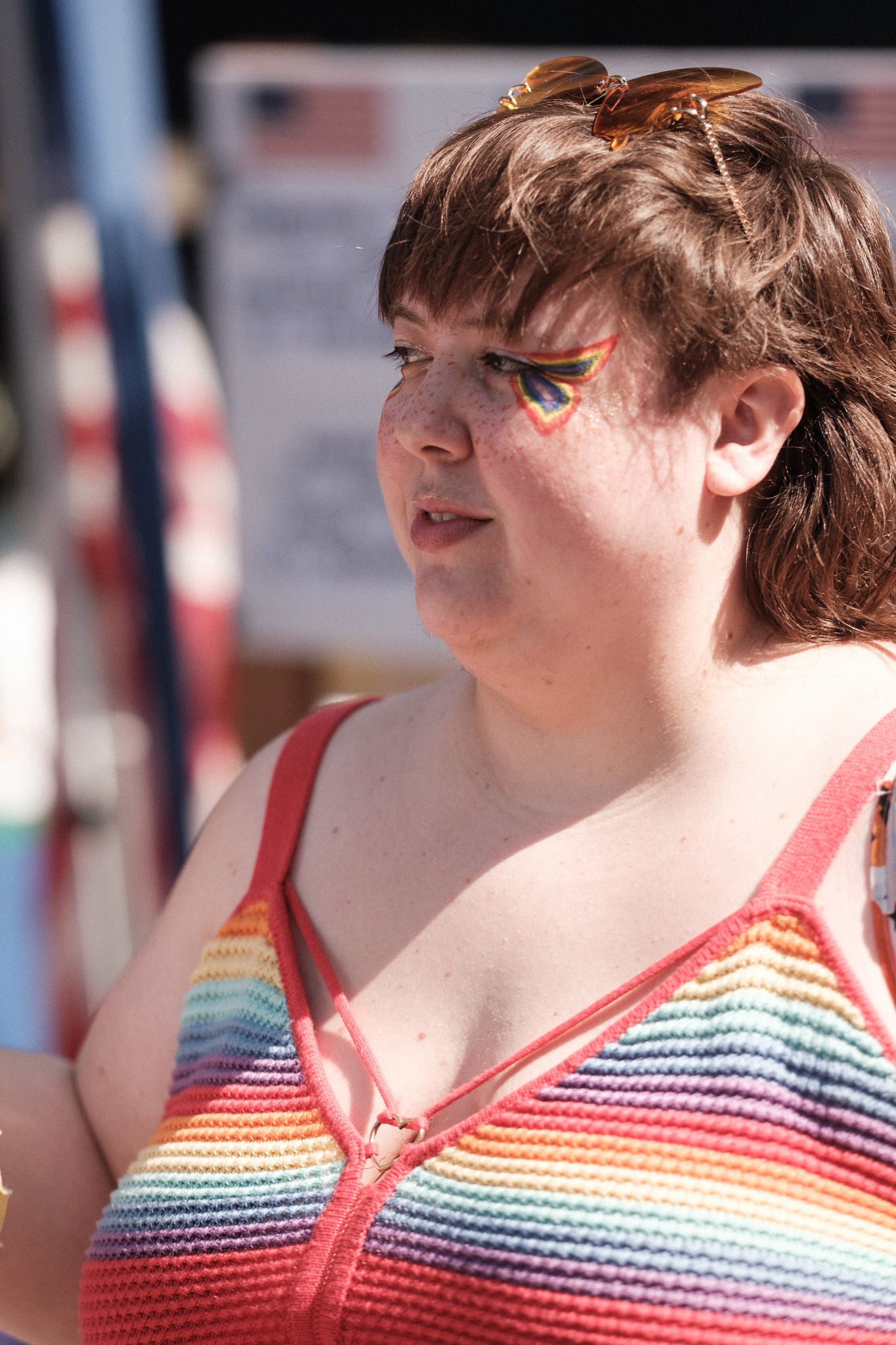 Festival attendee wearing a colorful rainbow striped tank top with face paint at an outdoor summer event.