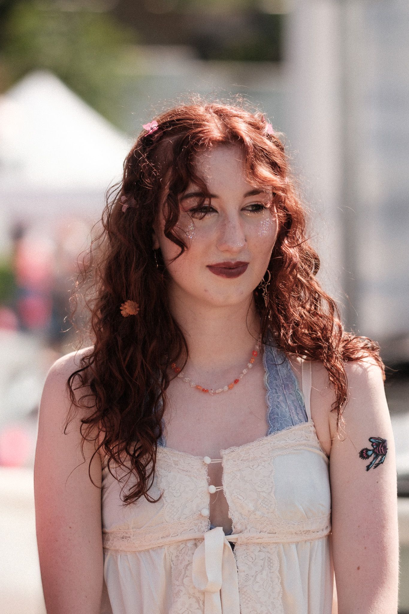 A festival attendee in a white lace dress with curly hair and vintage-inspired makeup.