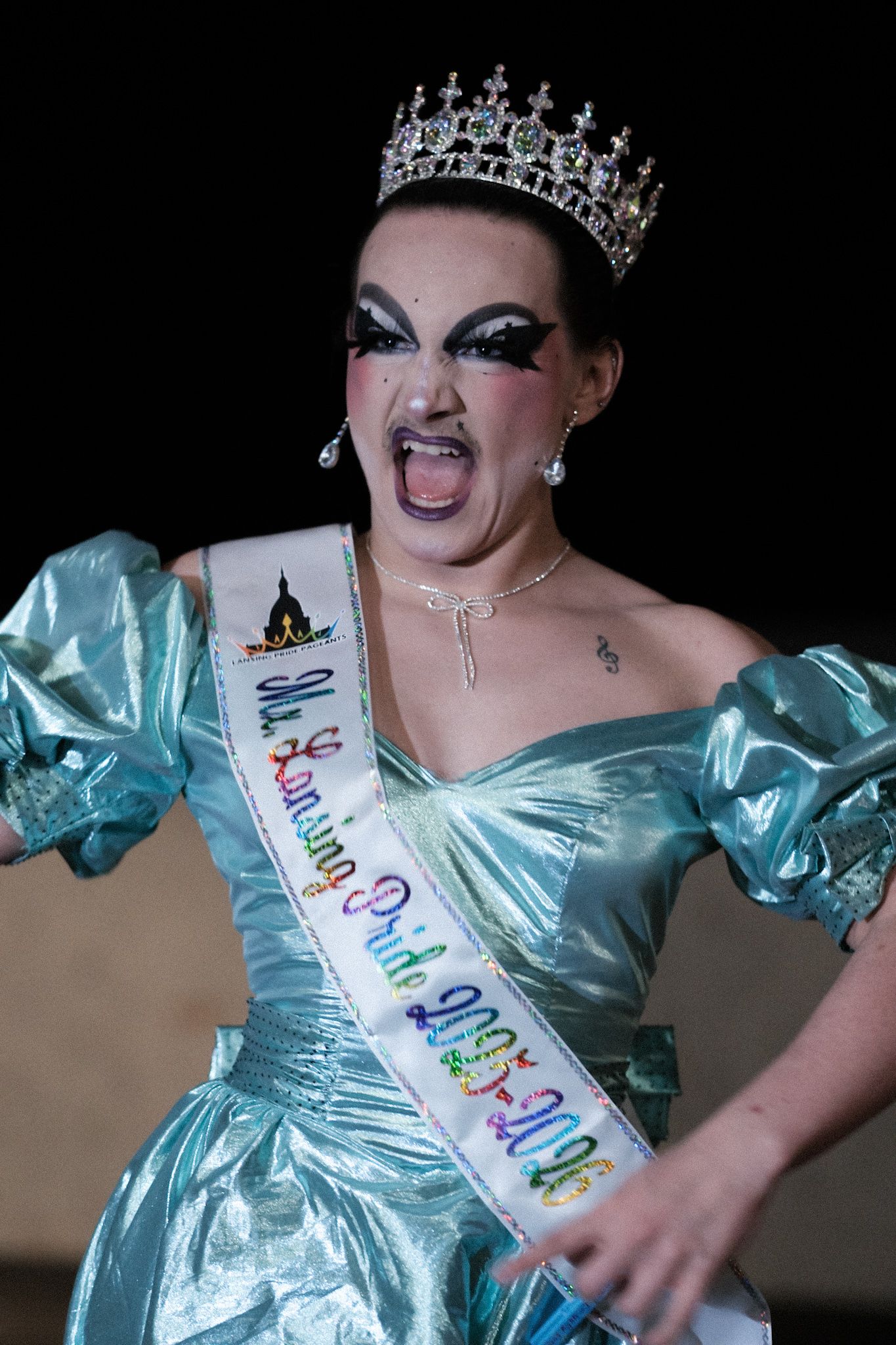 Performer in light blue gown wearing crown and sash during pageant performance.