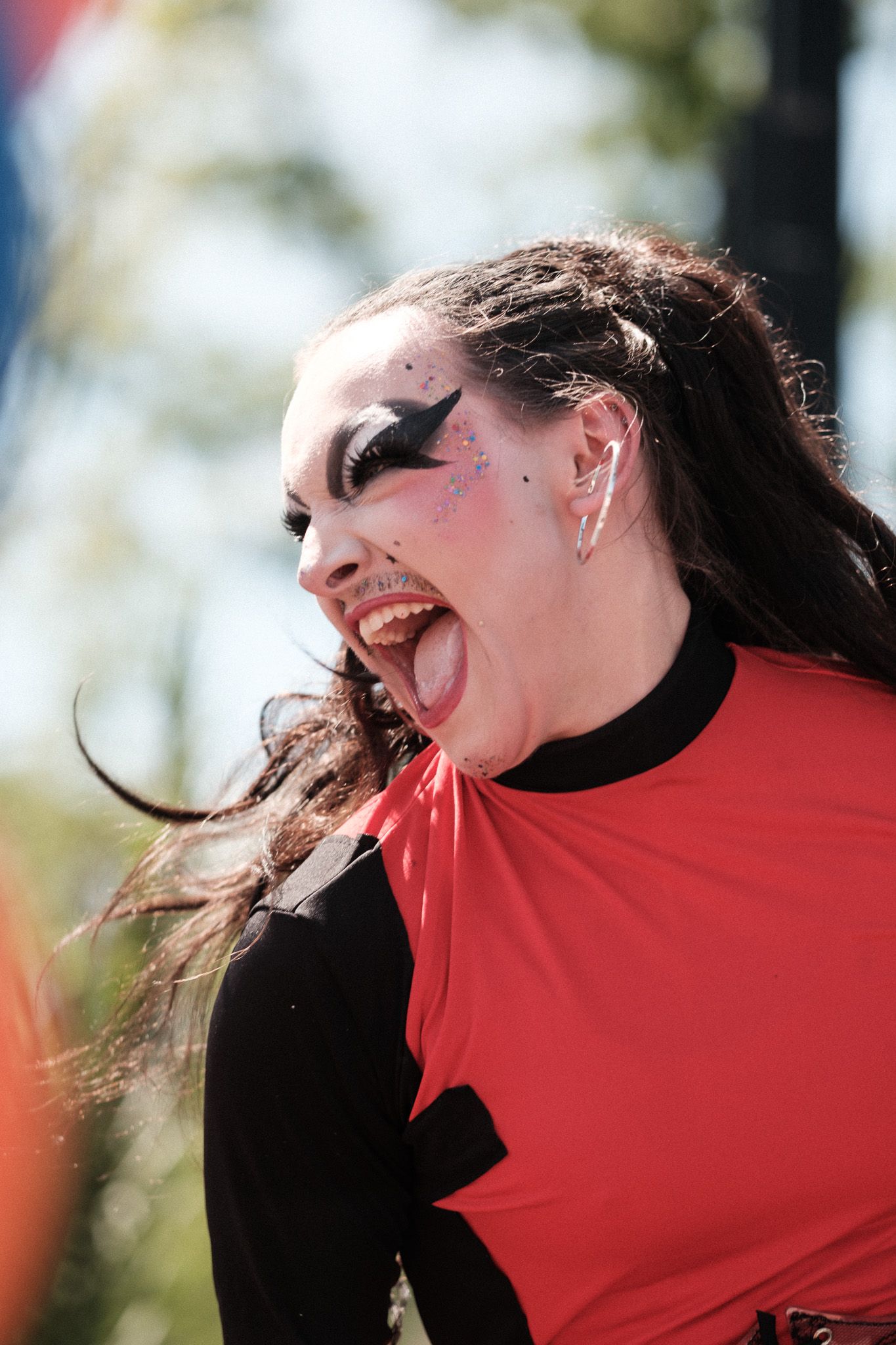 A theatrical performer in red and black clothing with dramatic stage makeup.