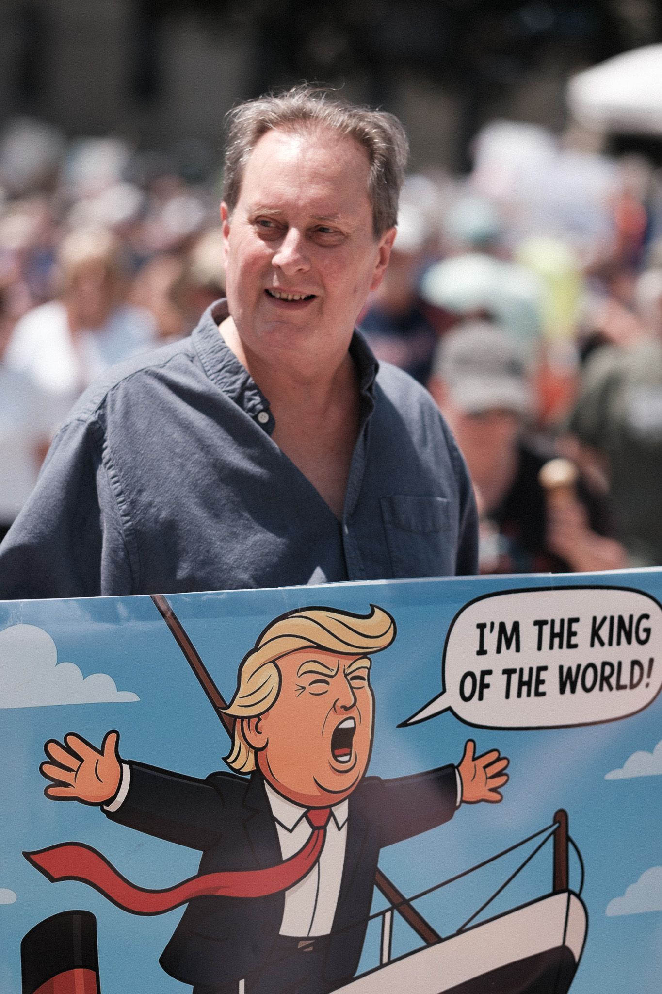 A protest sign shows a cartoon illustration declaring 'I'm the King of the World'.