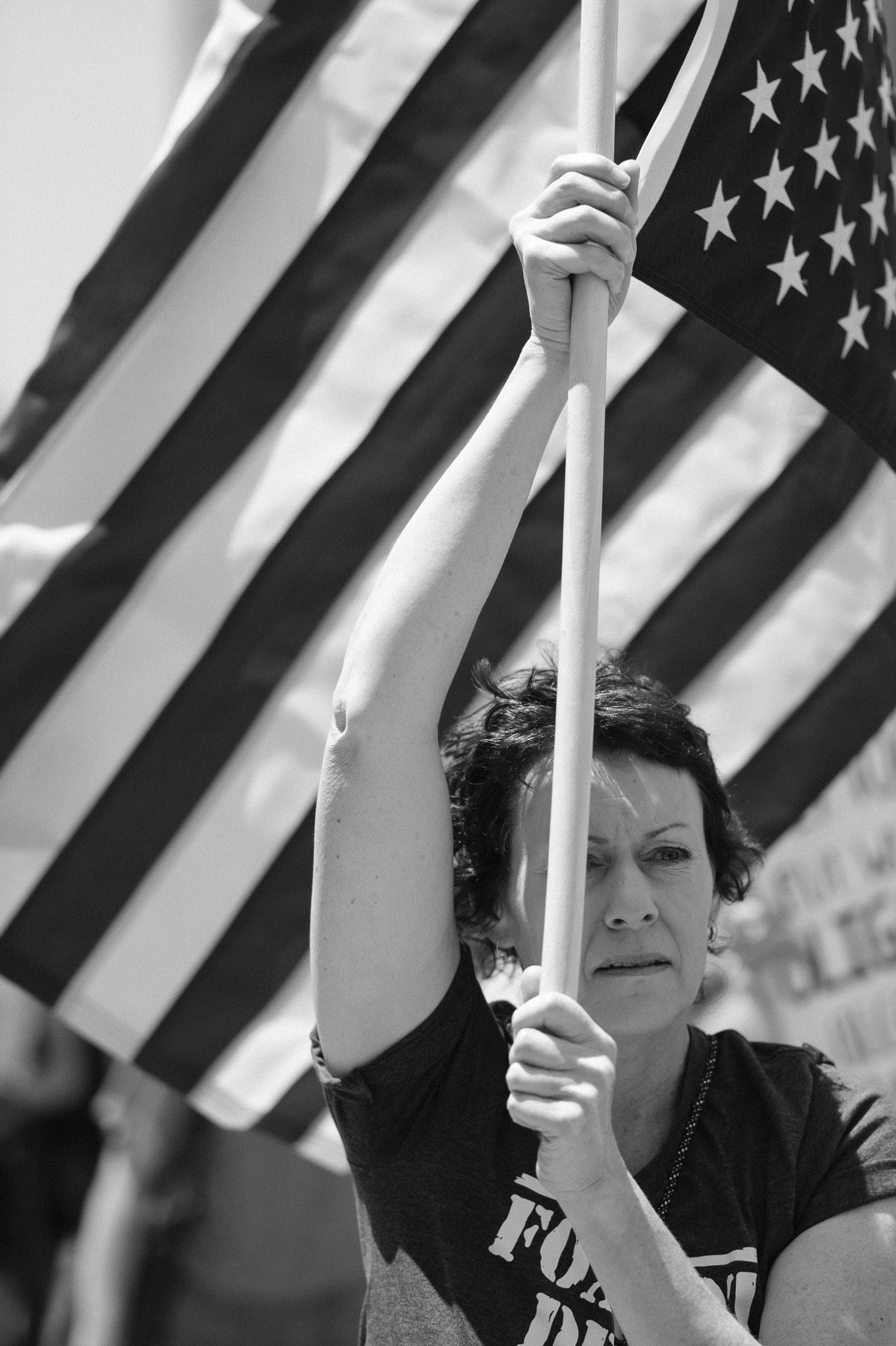 Protesters holding American flags against a striped flag backdrop during a demonstration.