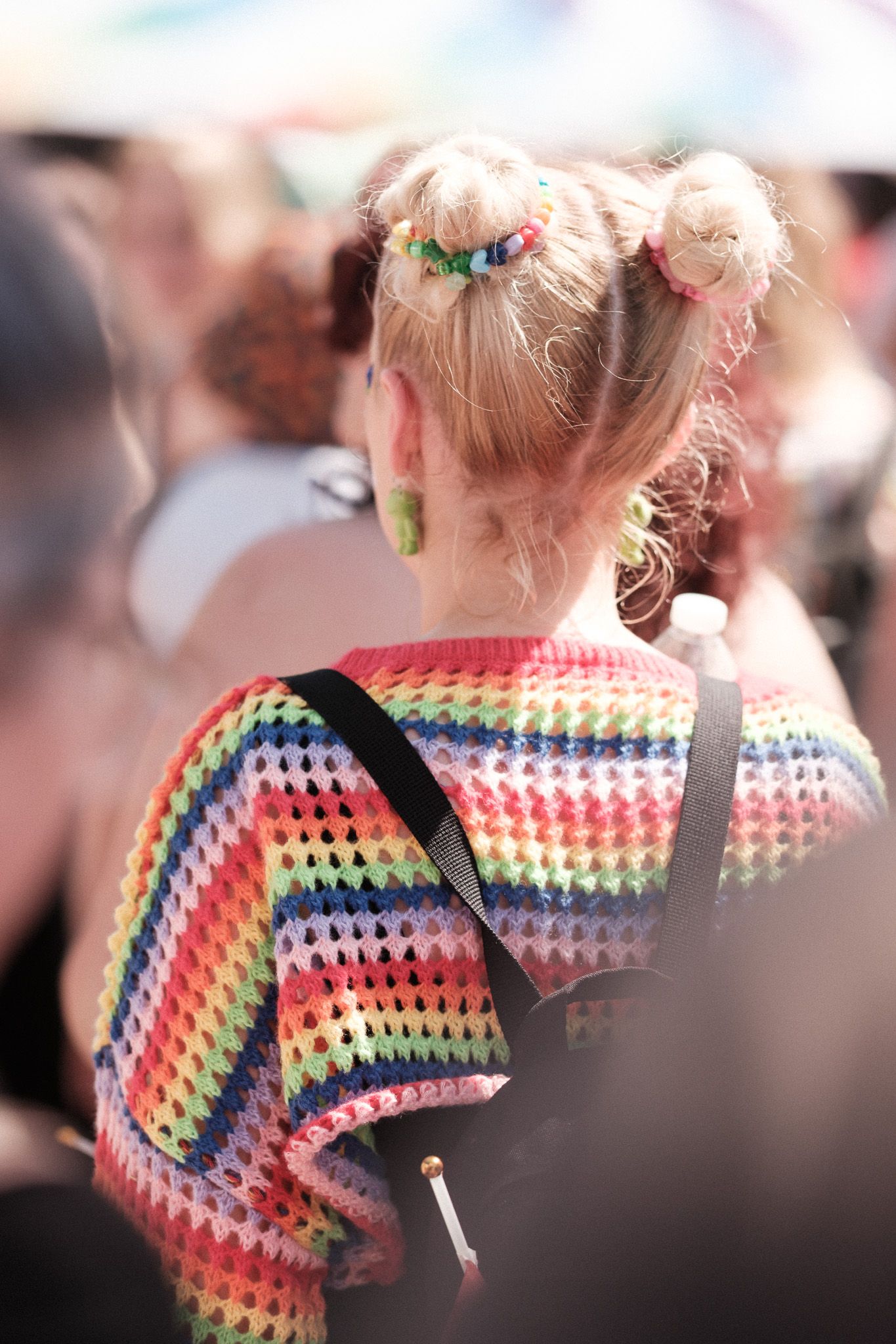 A series of photos showing someone wearing a colorful rainbow crochet shawl in a granny-stripe pattern.