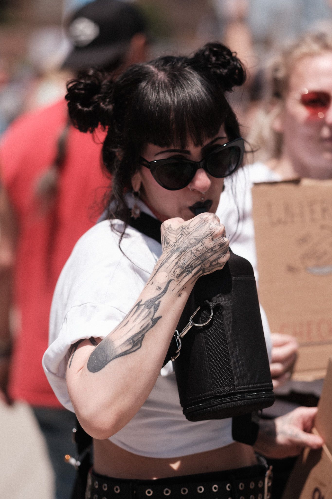 Person wearing sunglasses and dark clothing at an outdoor protest event.