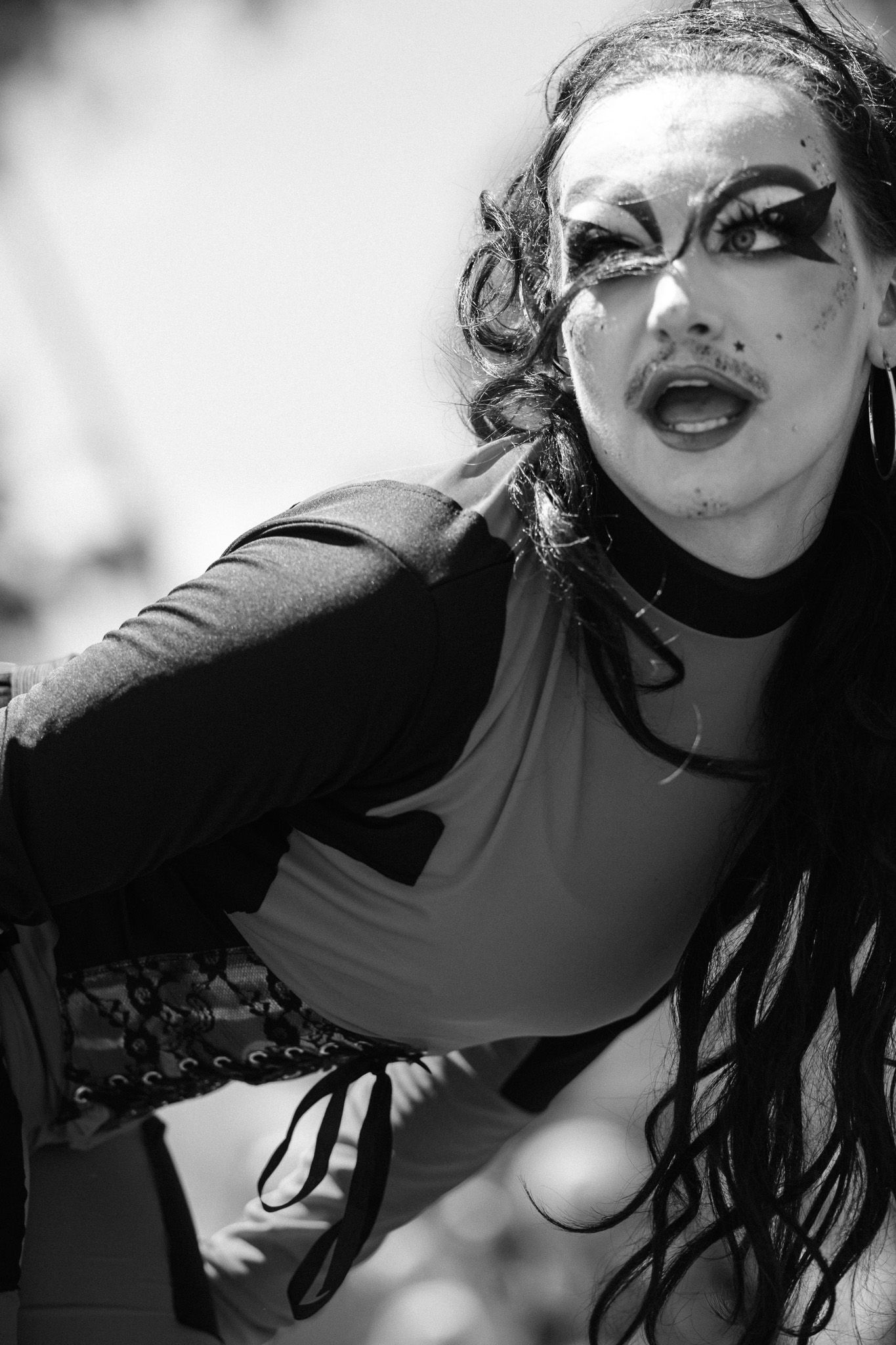 Dramatic black and white portrait of a performer in dramatic makeup and dark clothing.