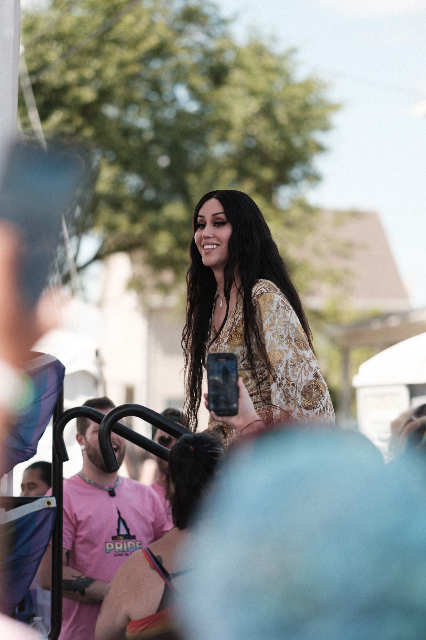 Performer in a floral dress entertains an outdoor crowd at a summer festival event.
