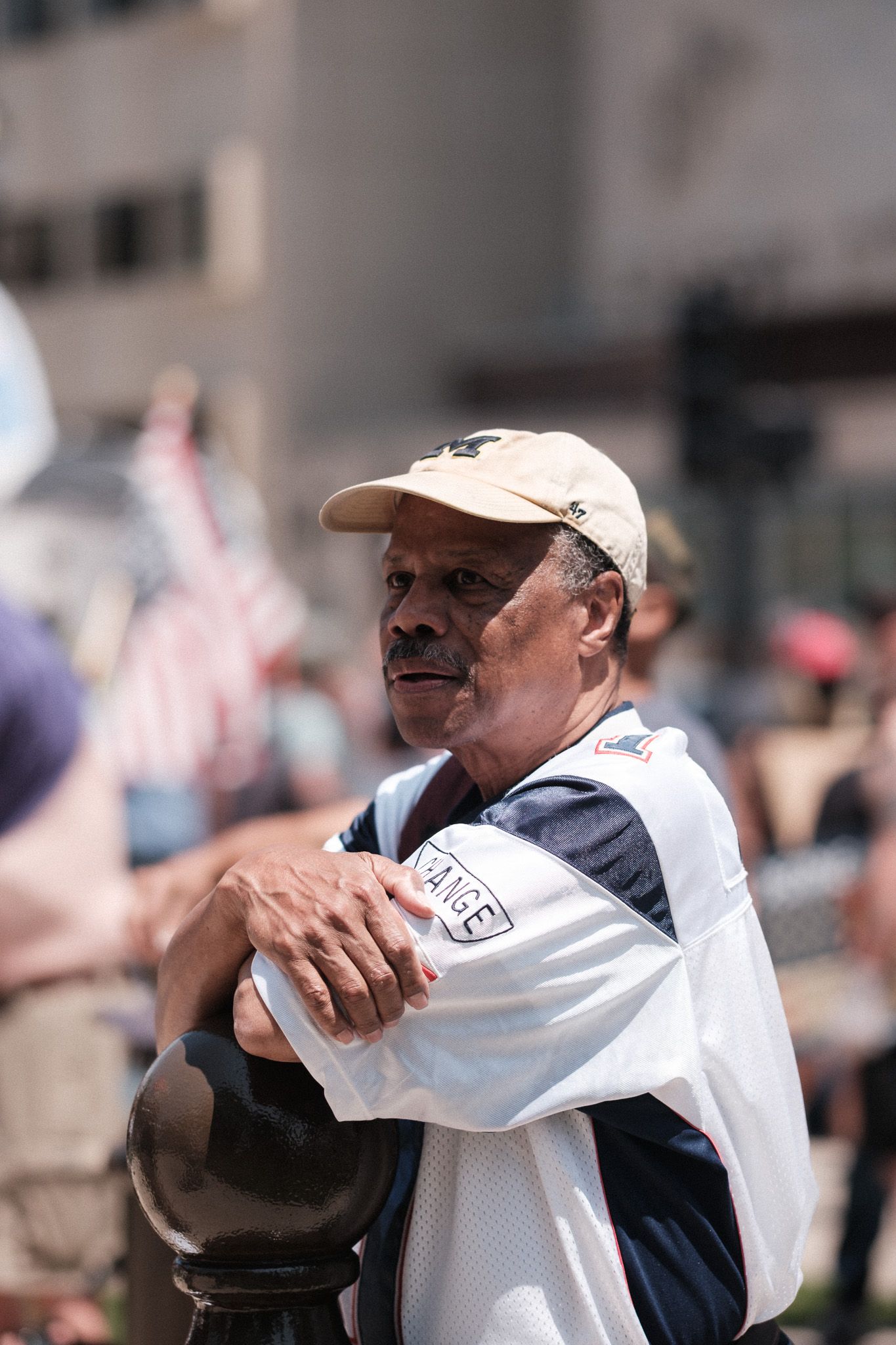 A protester in a white cap and sunglasses gestures emotionally during a demonstration.
