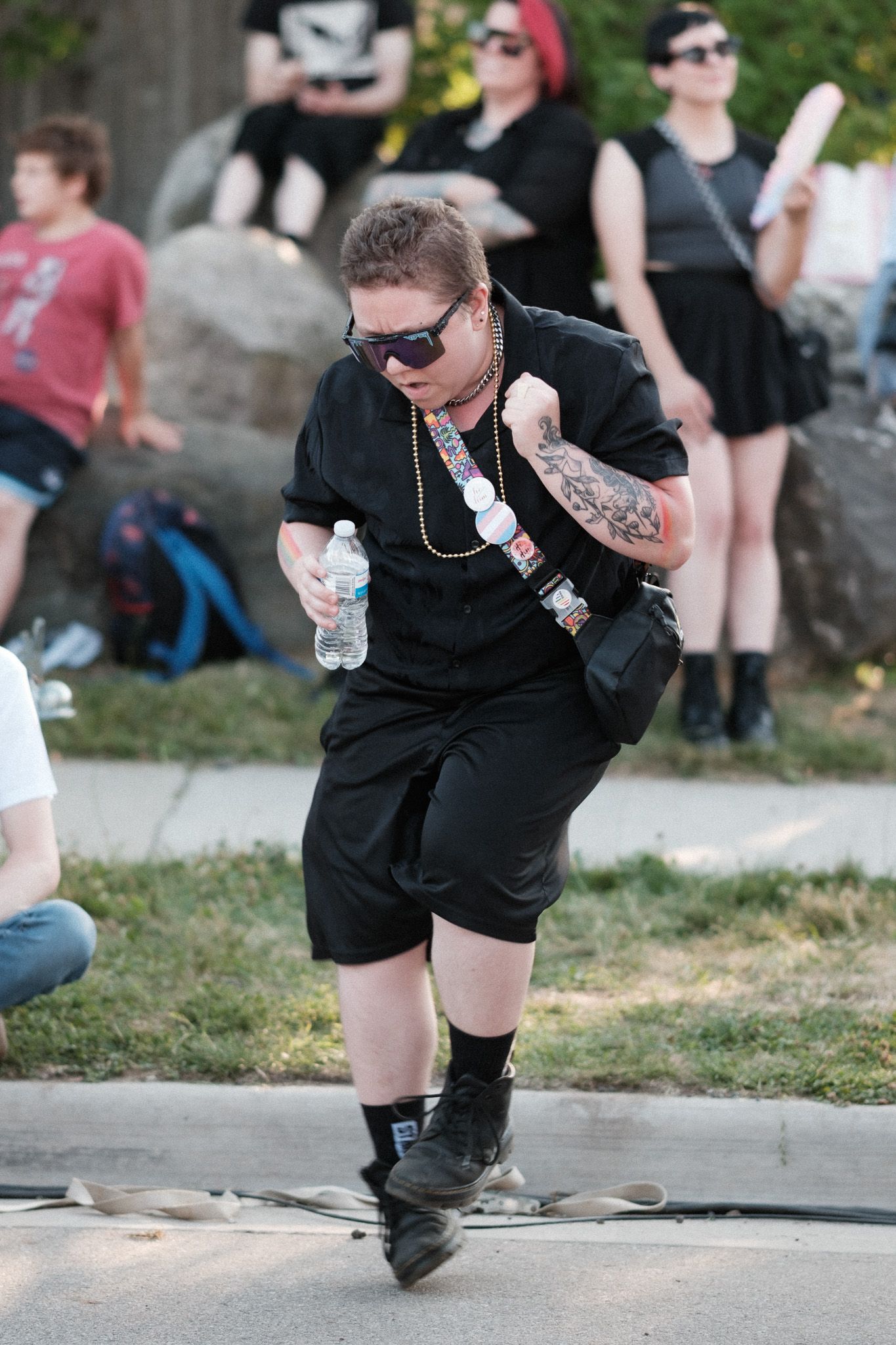 Person in black clothing crouching down during an outdoor performance or event.