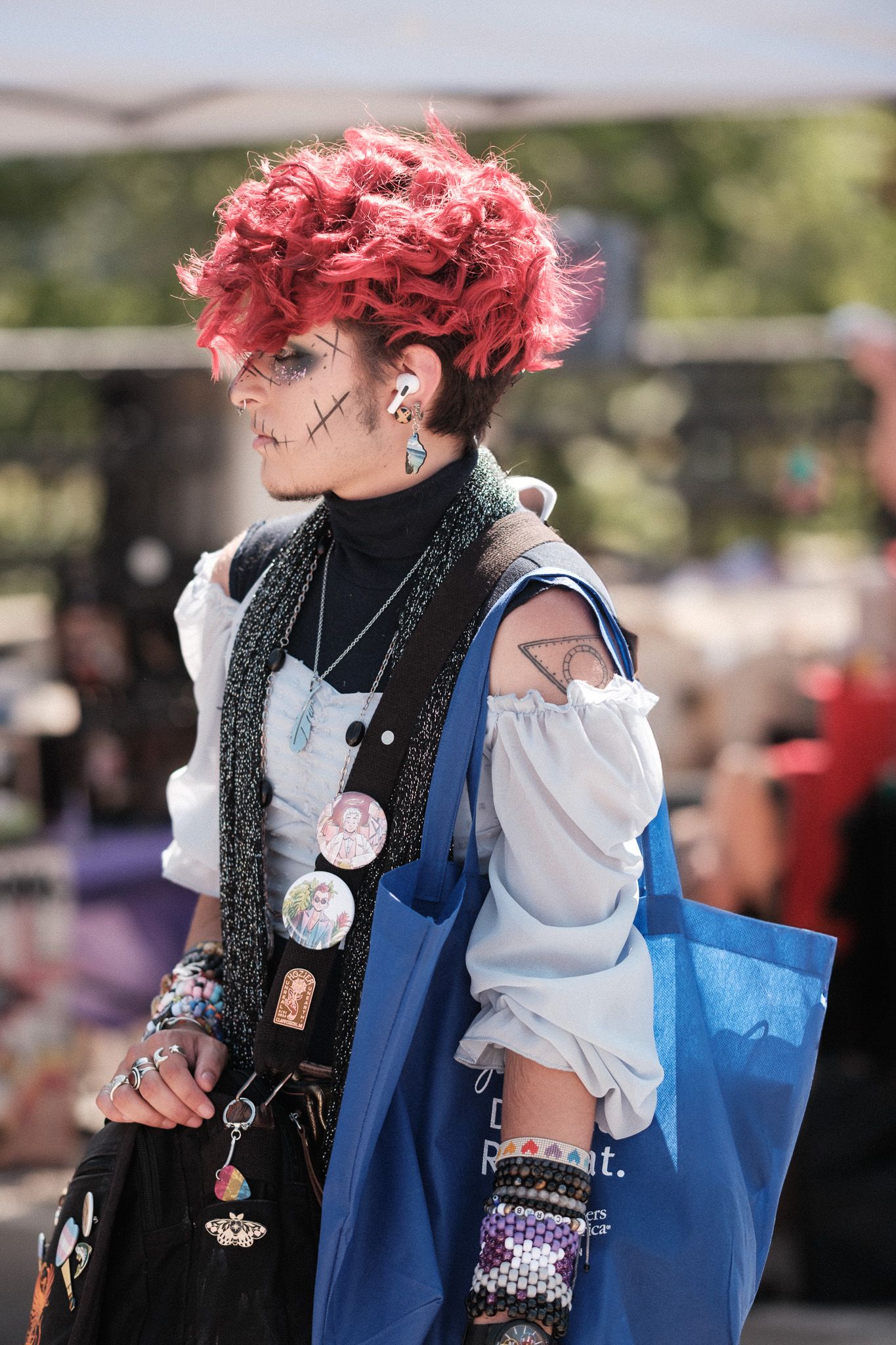 Alternative fashion look featuring bright pink hair, white blouse and black accessories at an outdoor event.