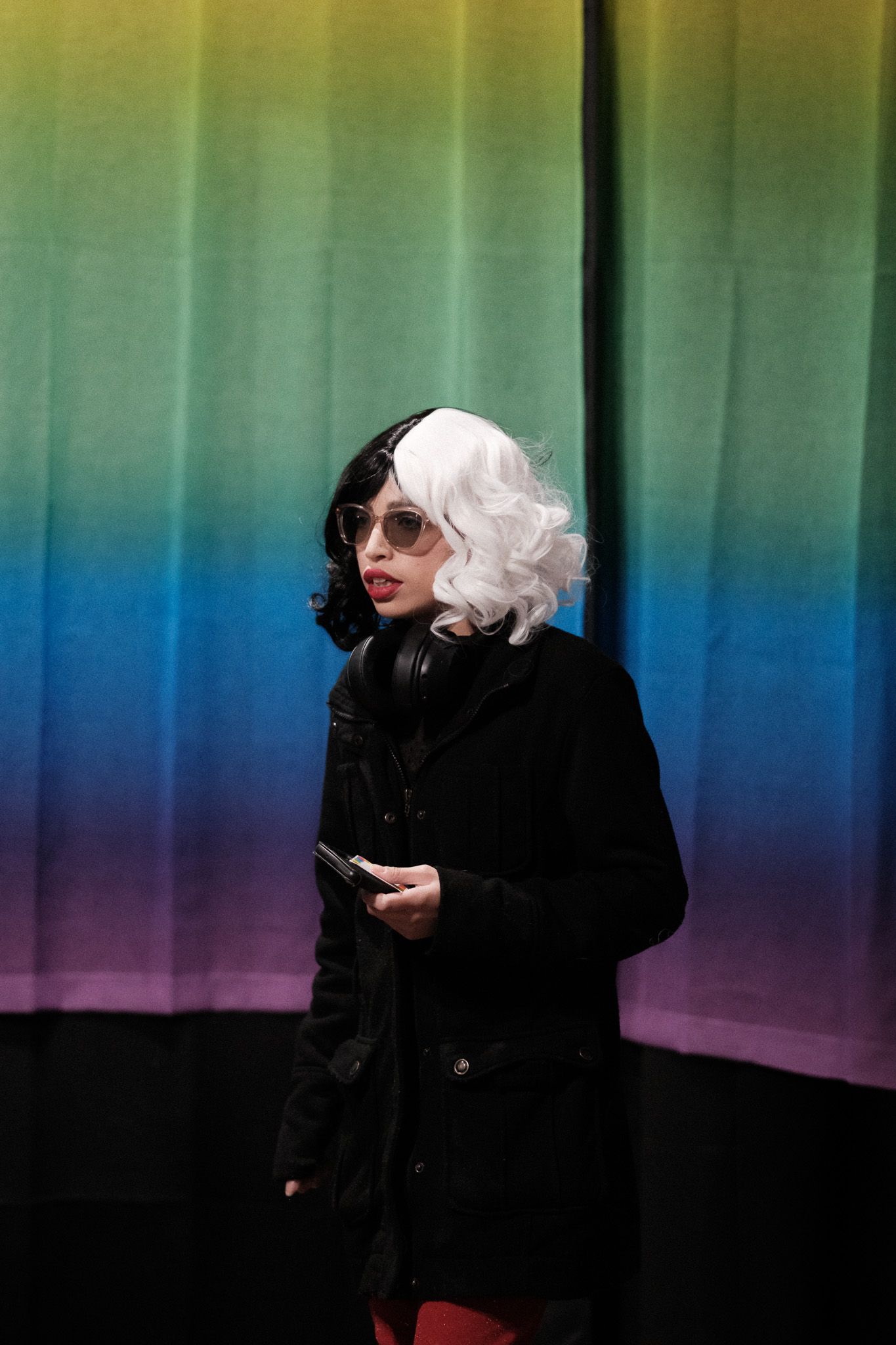 Figure in black clothing and white hair poses against colorful gradient wall showing multiple dynamic movements.