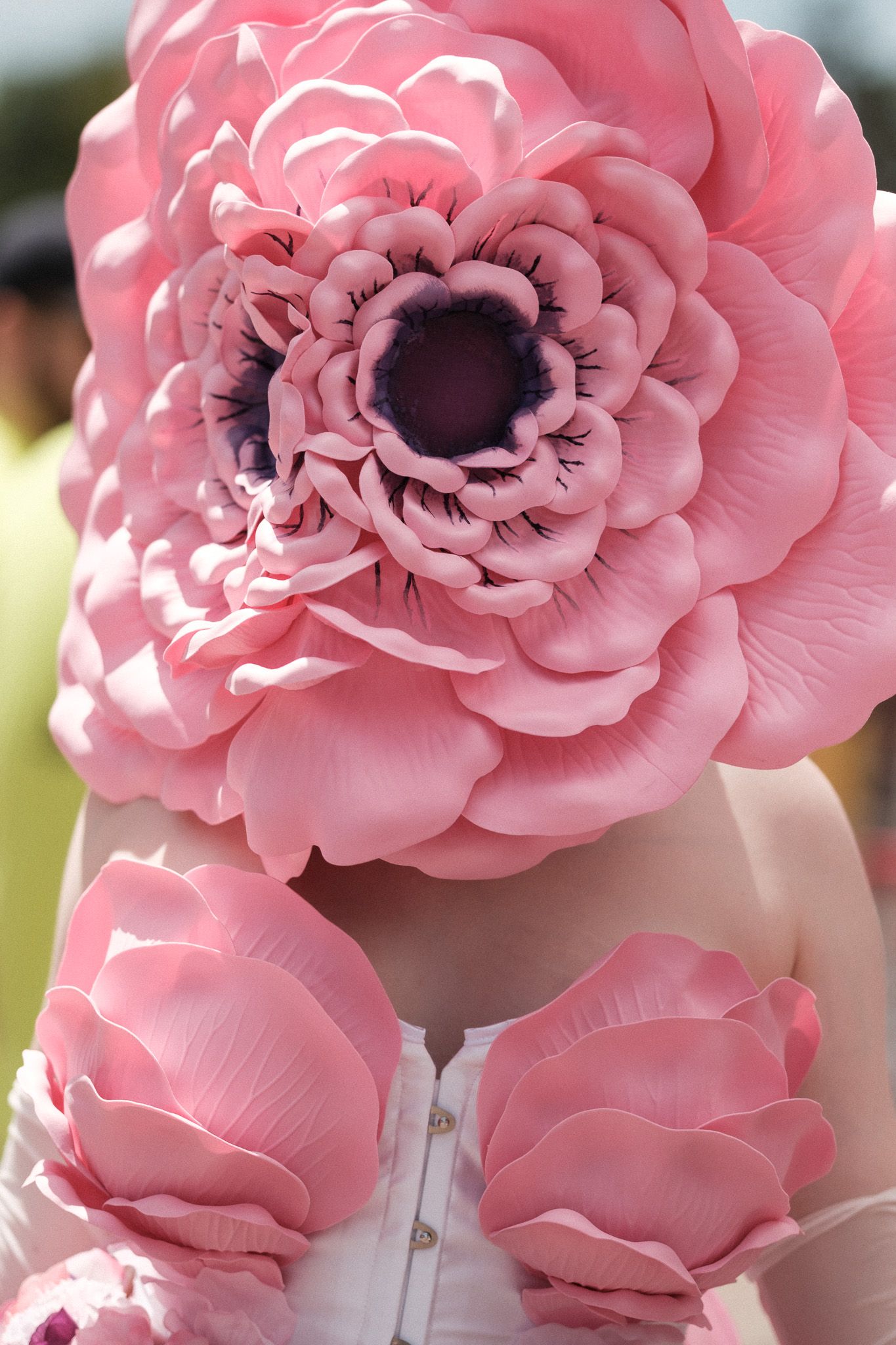 Large pink floral decorations adorn a white corset, creating a whimsical romantic detail.