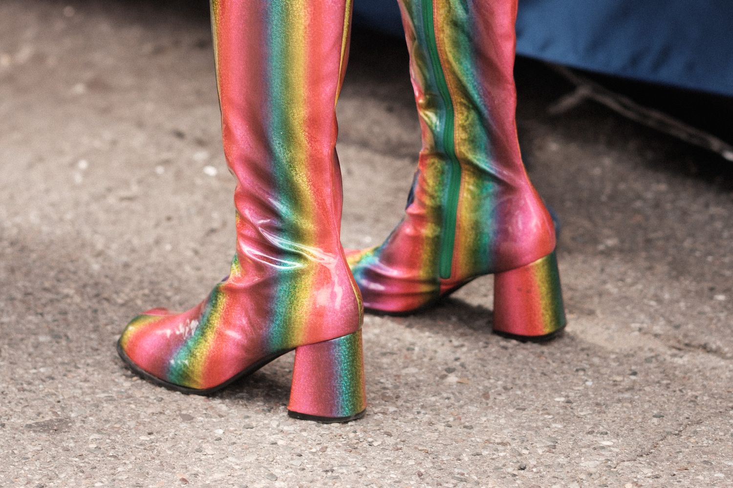 Colorful rainbow striped platform boots with chunky heels photographed on concrete ground.