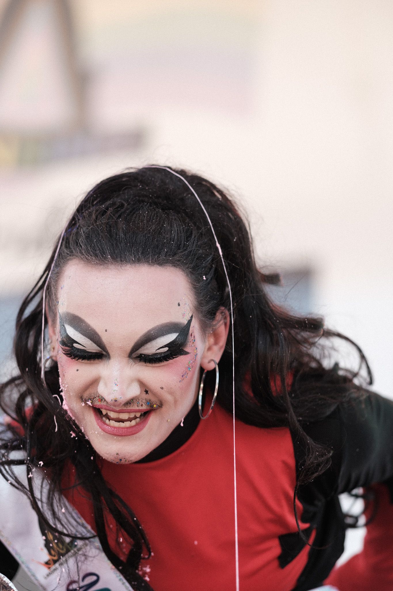 A dramatic performer in theatrical makeup and red costume shows expressive emotions.