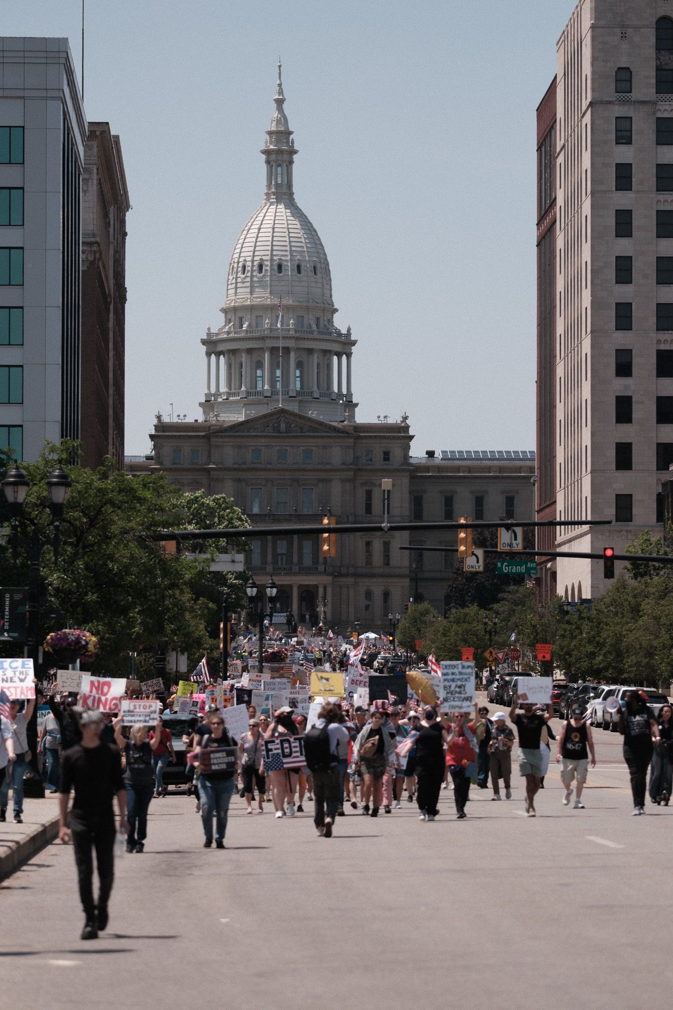 Protesters march toward state capitol building with signs during political demonstration.