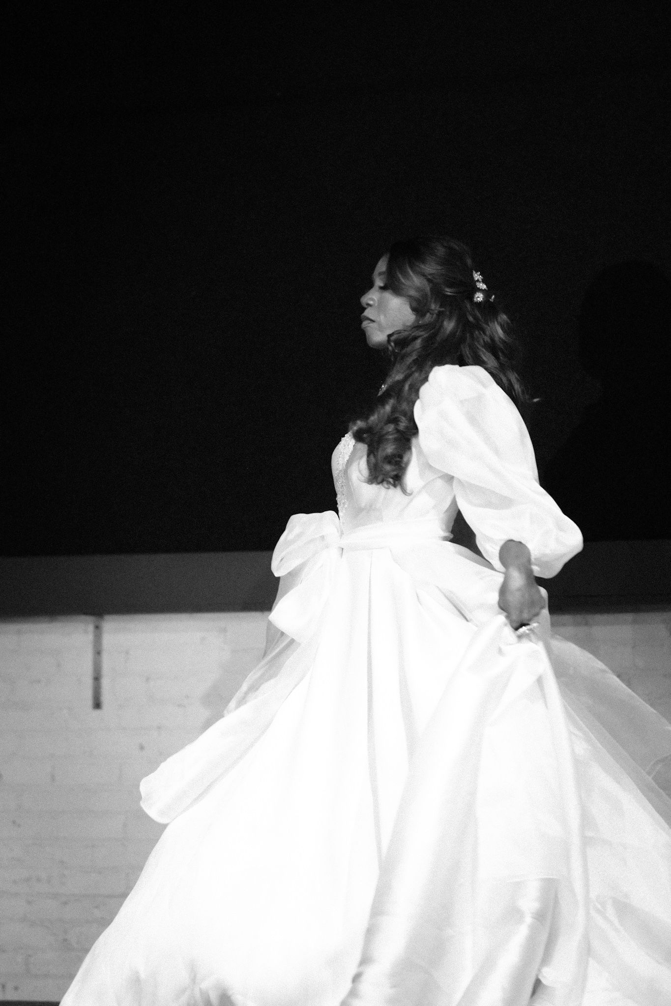 Dramatic black and white photo of a flowing white ballgown in motion during a performance.