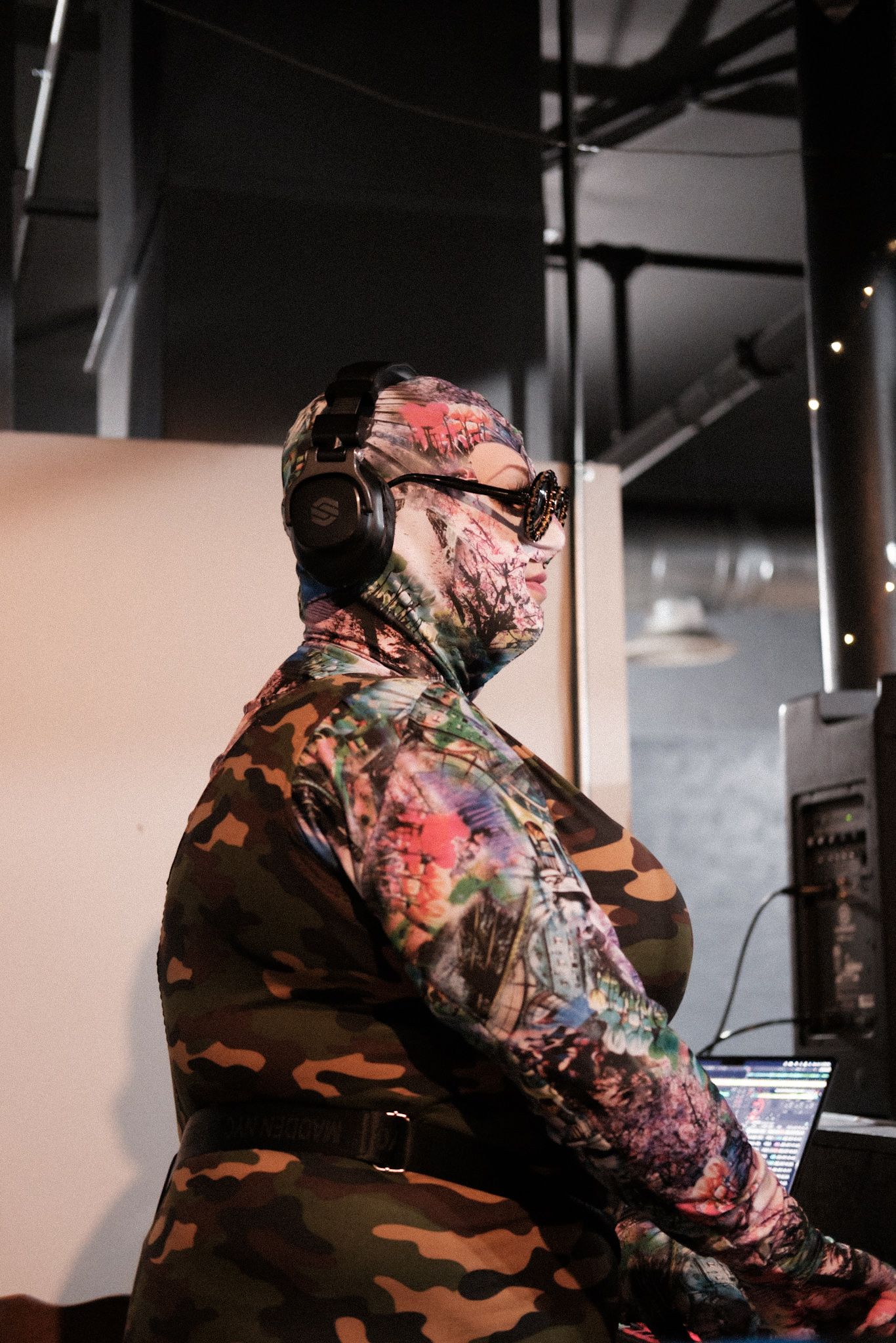 Side profile of person wearing camouflage jacket in dim lighting.