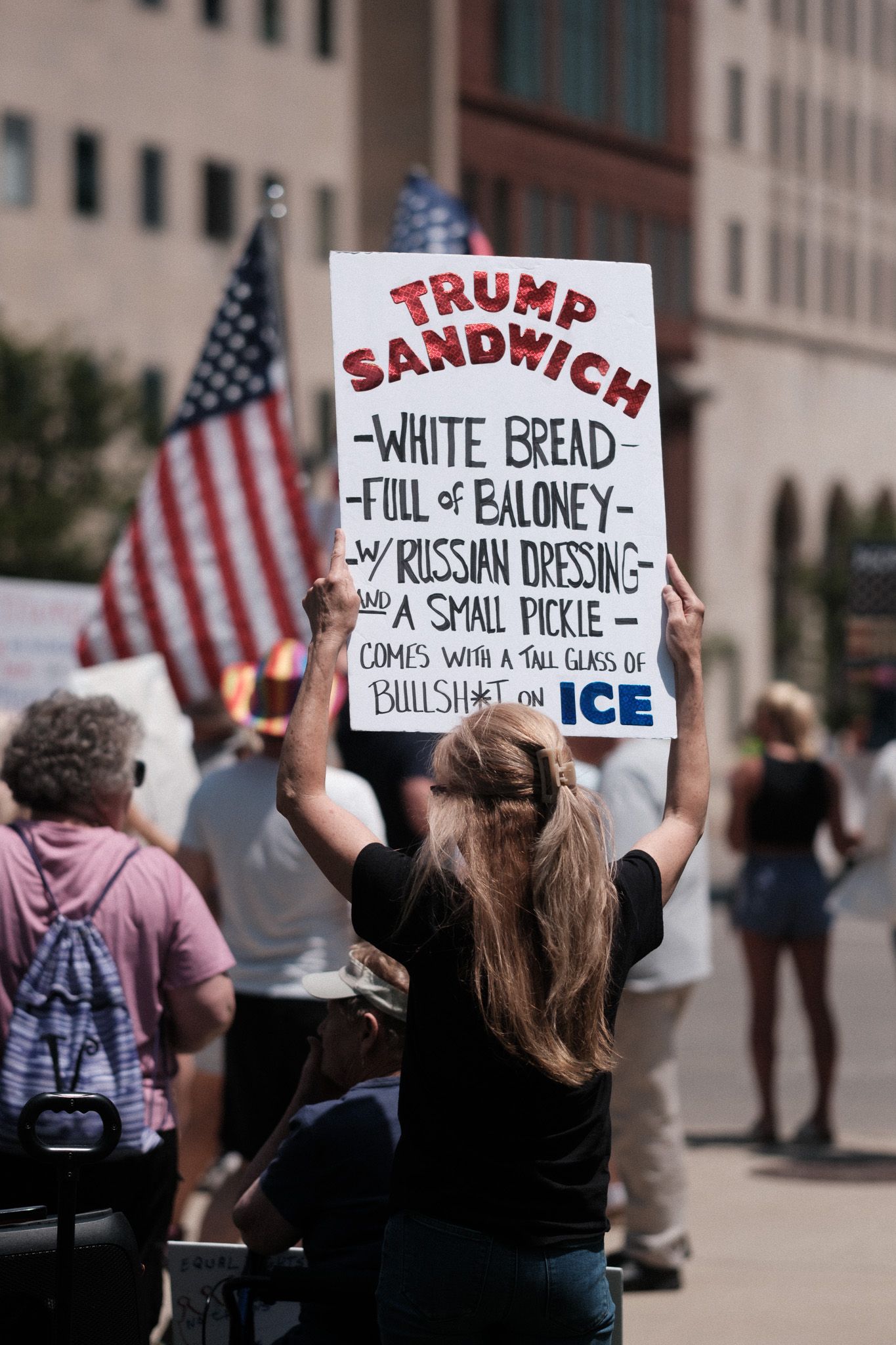 Protest signs with messages referencing food items and Russian dressing at a political demonstration.