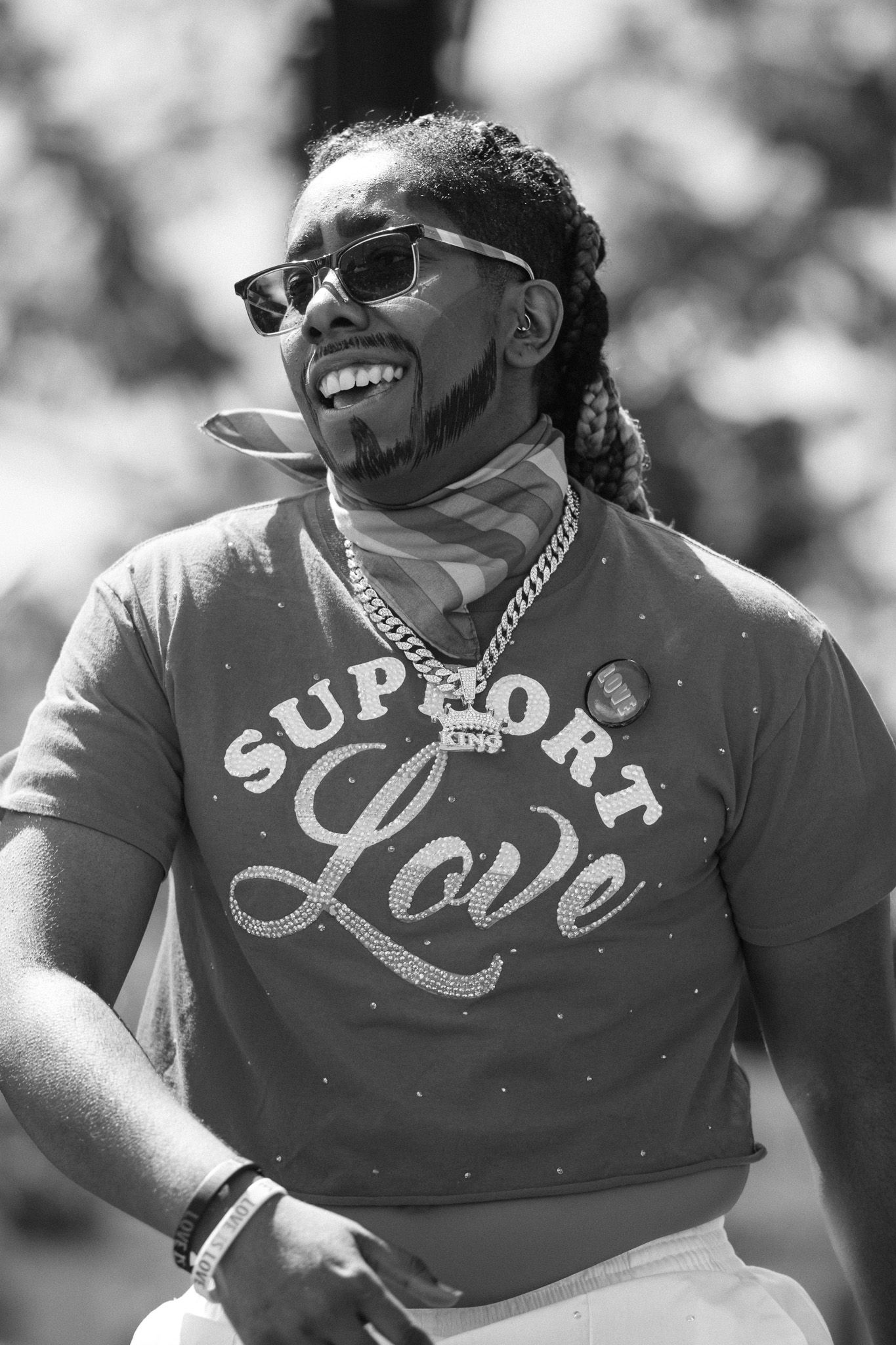 Three black and white photos of someone wearing a t-shirt with Love text while smiling and wearing sunglasses outdoors.