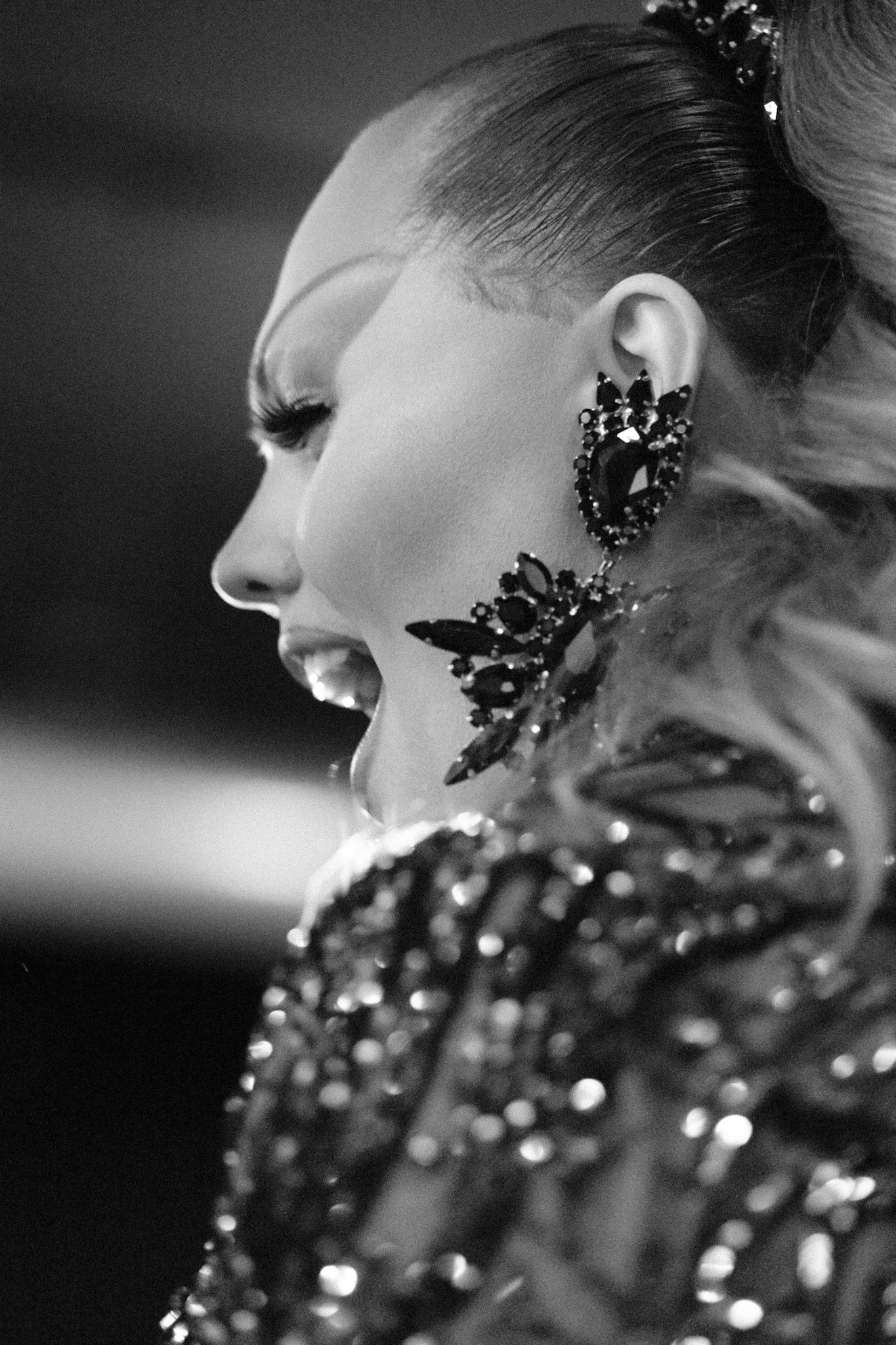 Close-up profile shot of a performer with dramatic makeup and crystal embellished jewelry.