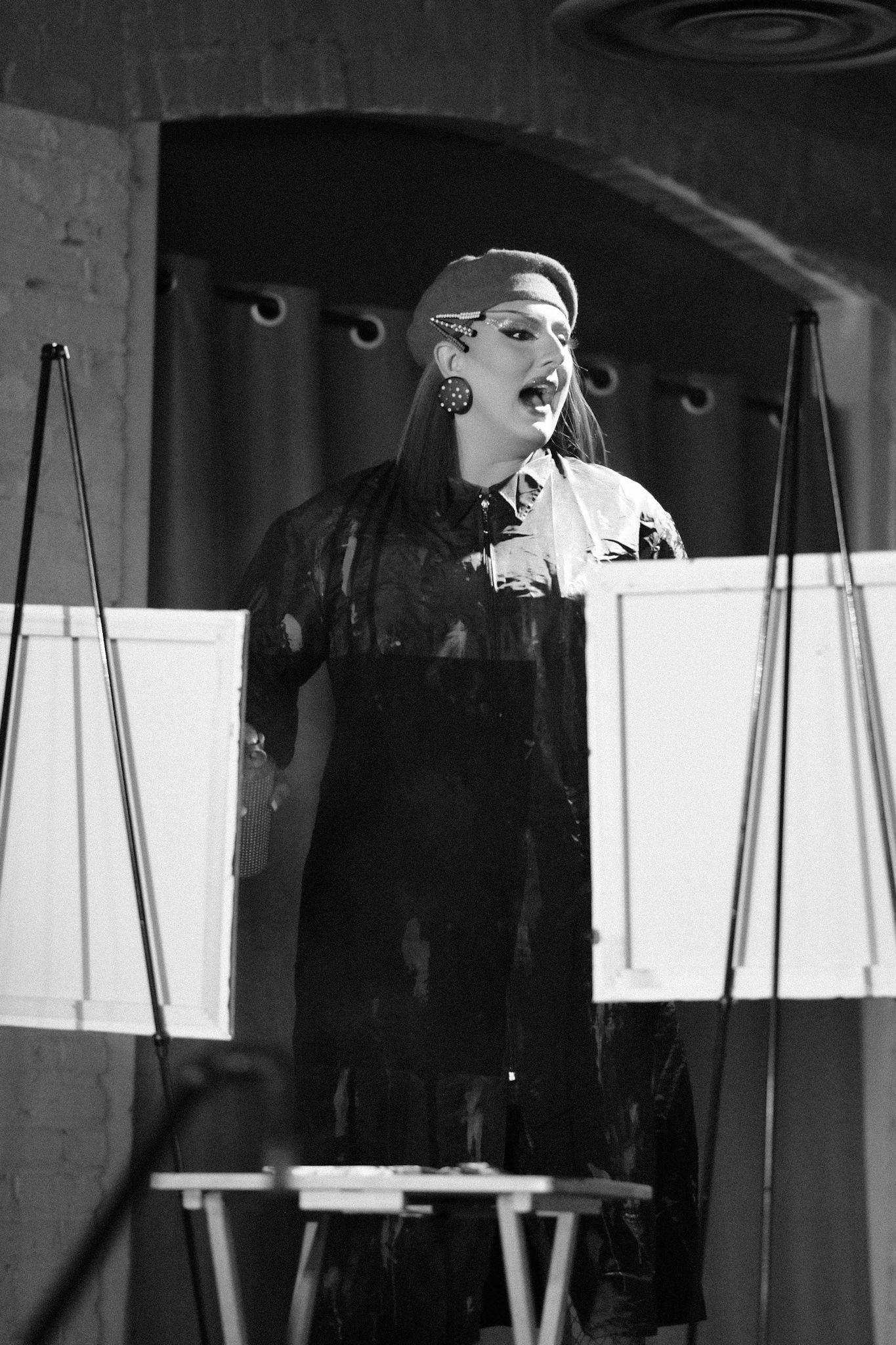 Dramatic black and white stage performance with theatrical lighting and curtains.