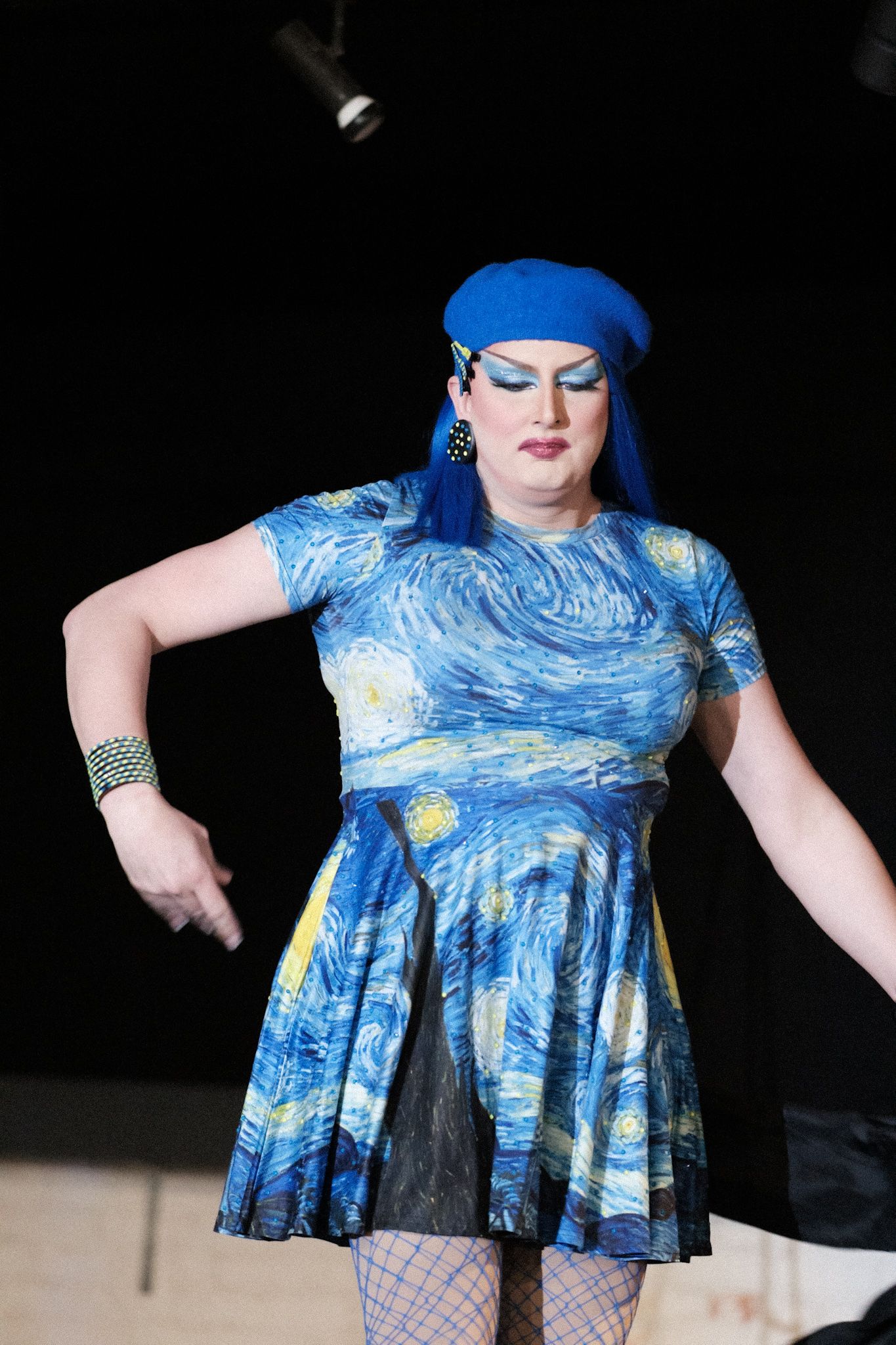 Performer wearing a Starry Night inspired dress and blue beret on stage.