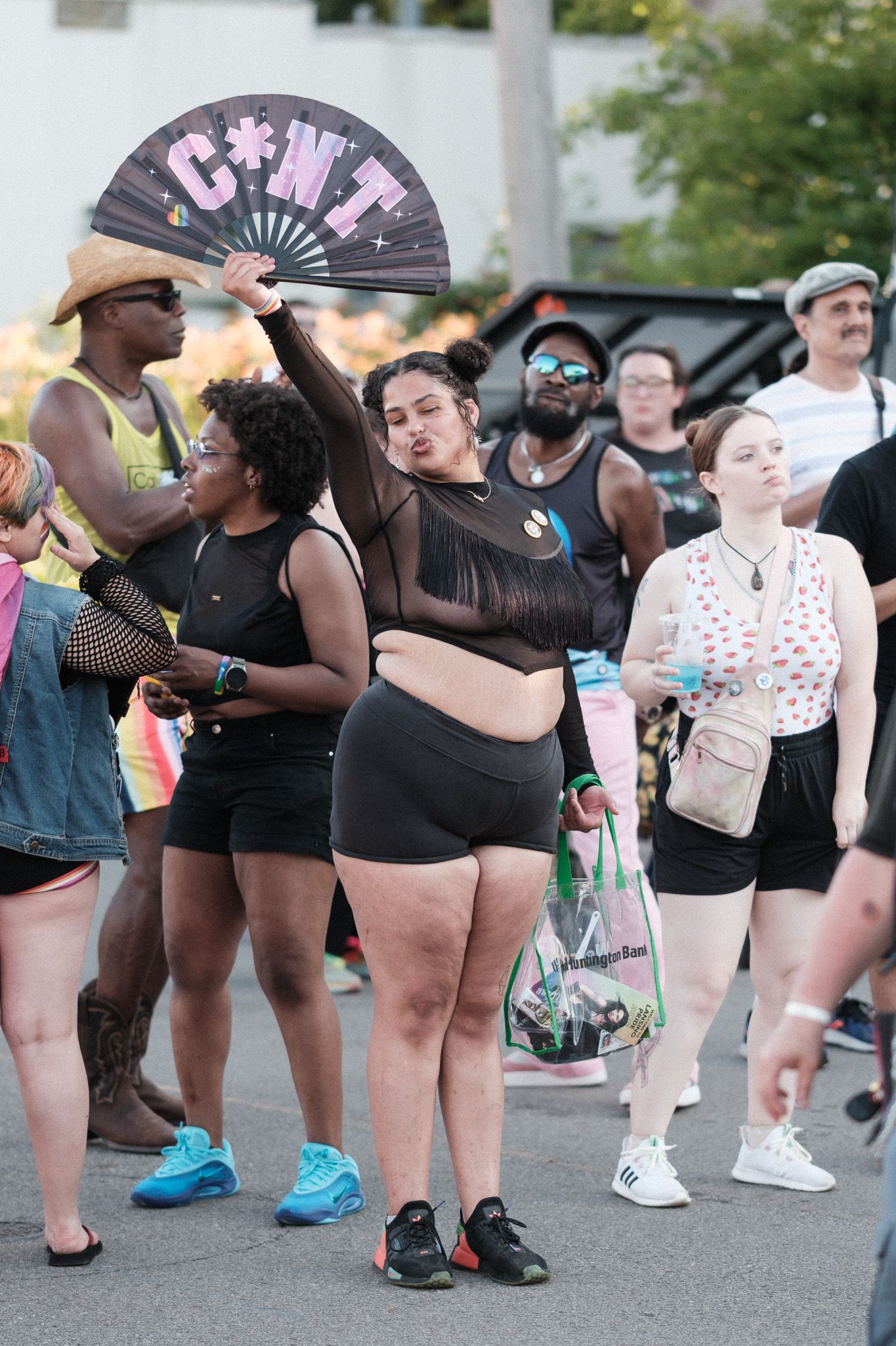 Diverse crowd of festival-goers with decorative fans gather at outdoor summer event.